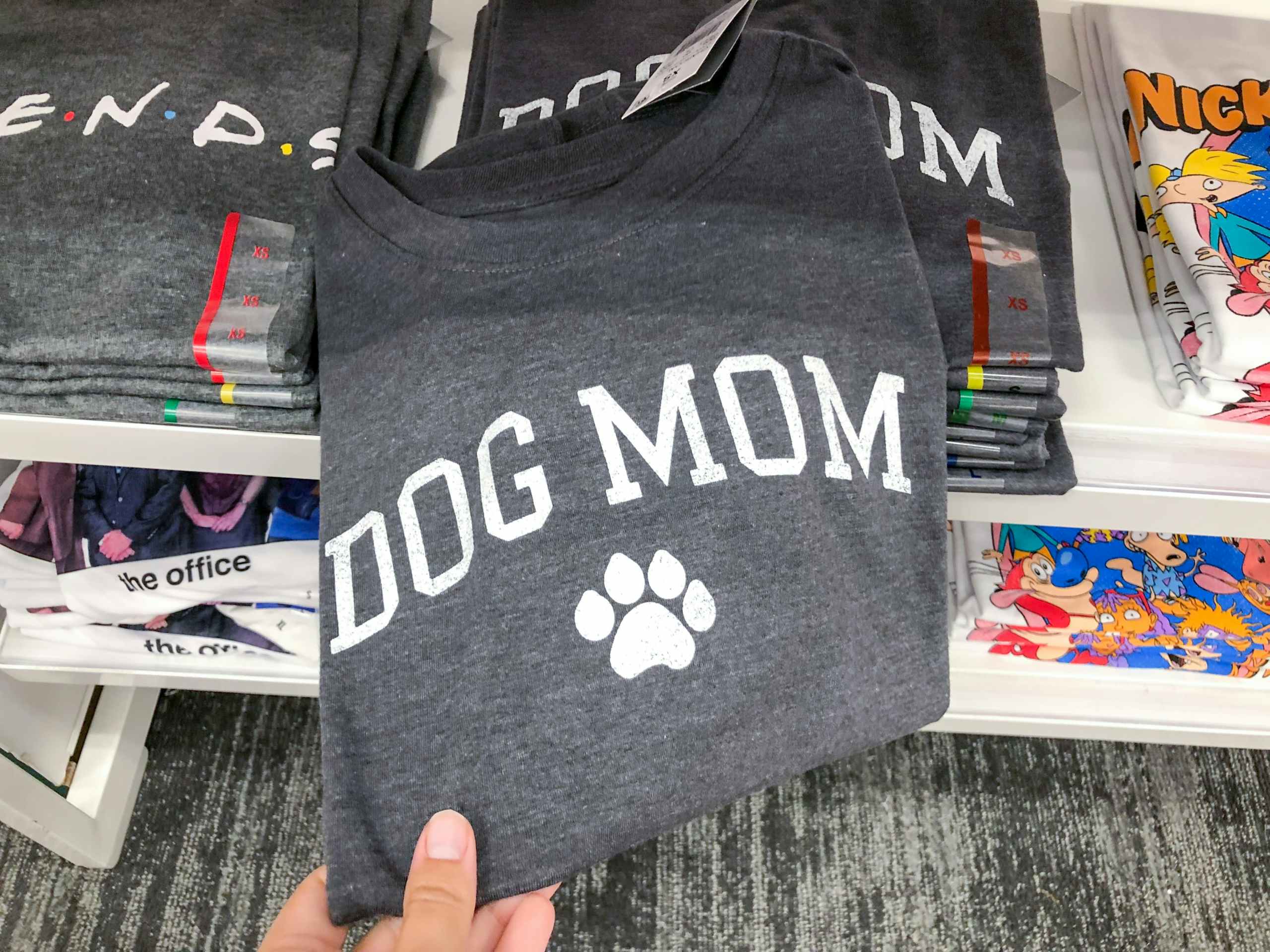 hand grabbing Dog Mom tee off Target store shelf