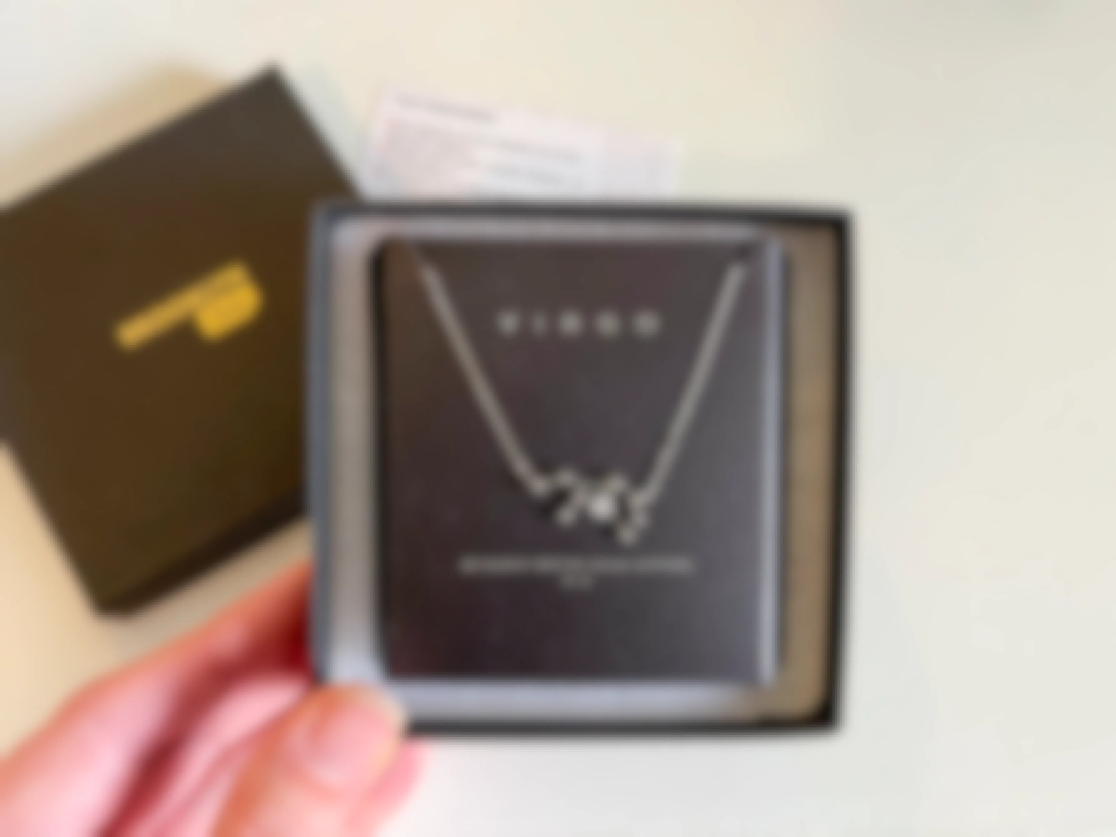 A Virgo zodiac symbol necklace in a black box.