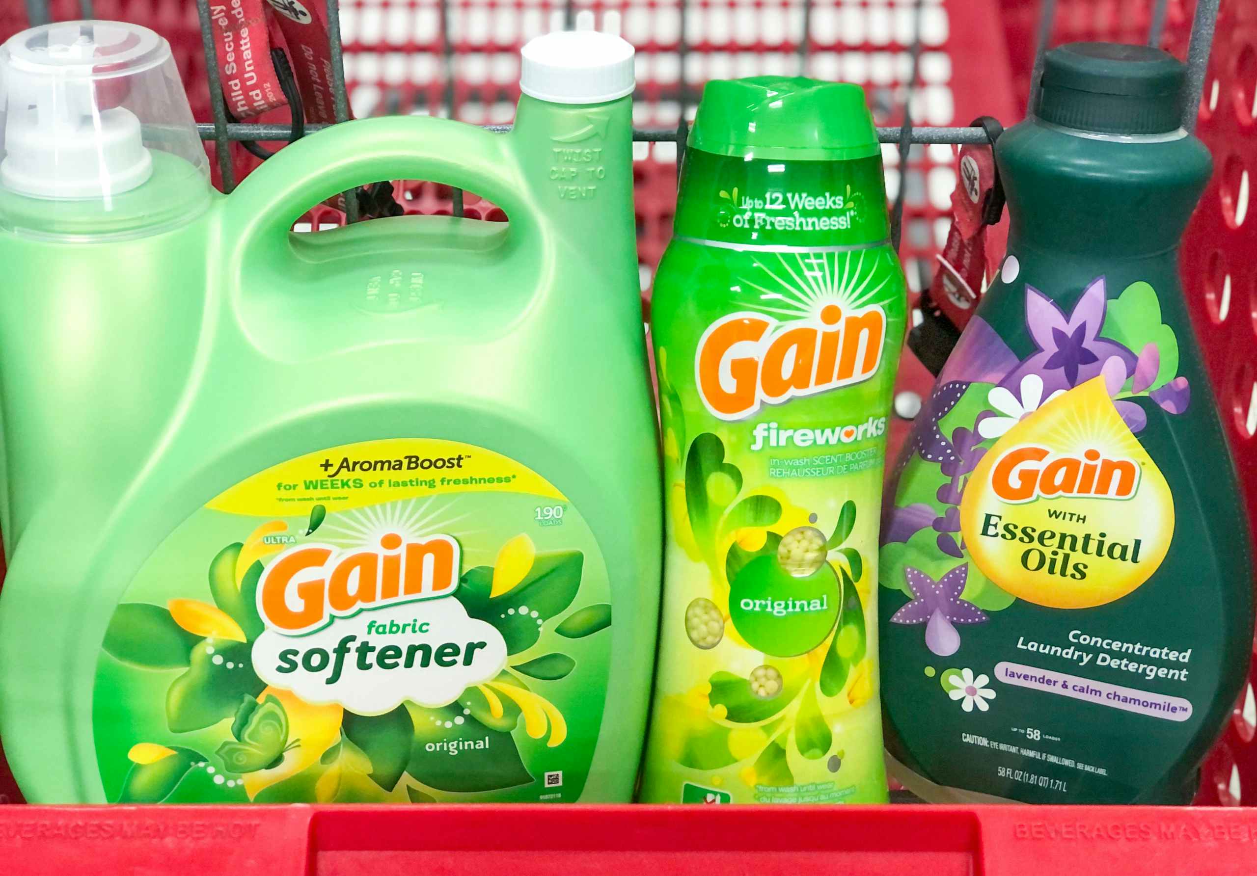three bottles of different Gain laundry care in the front compartment of a Target shopping cart