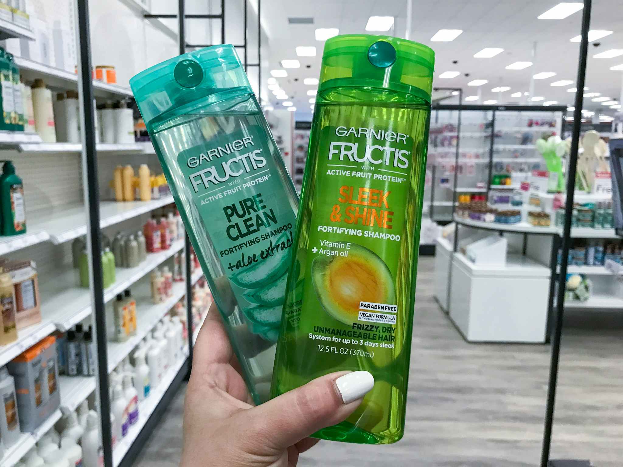 hand holding 2 bottles of garnier fructis shampoo at target