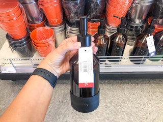 hand holding glass soap bottle in front of display shelf at Target