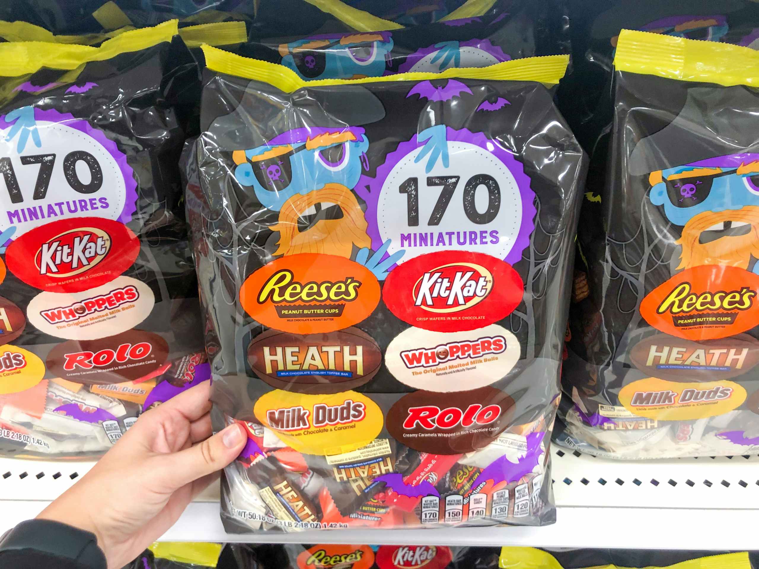 hand grabbing bag of Hallween candy off store shelf