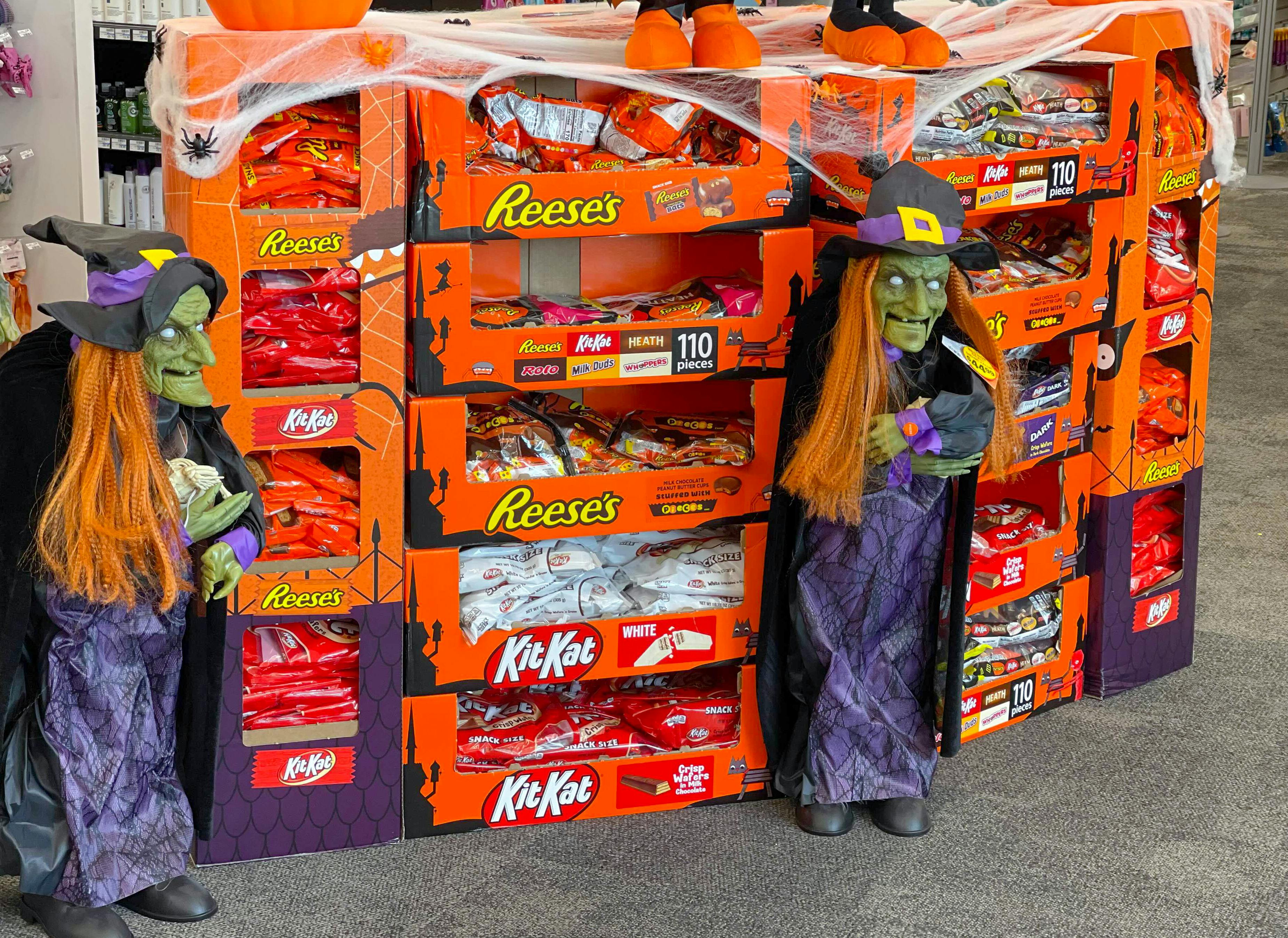A display of Halloween candy and some witch decorations at a store.