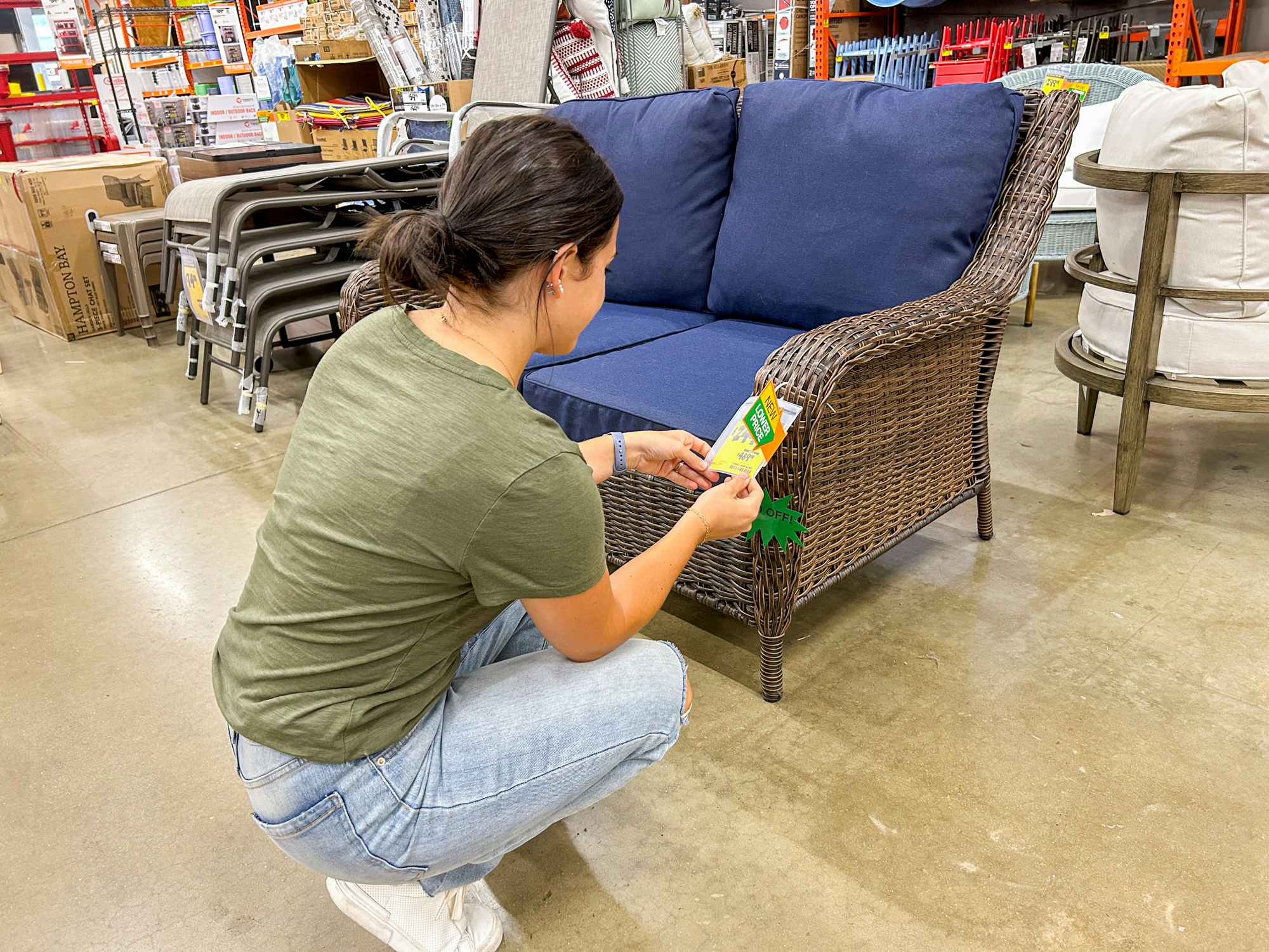 a person bending down looking at patio furniture in the home depot
