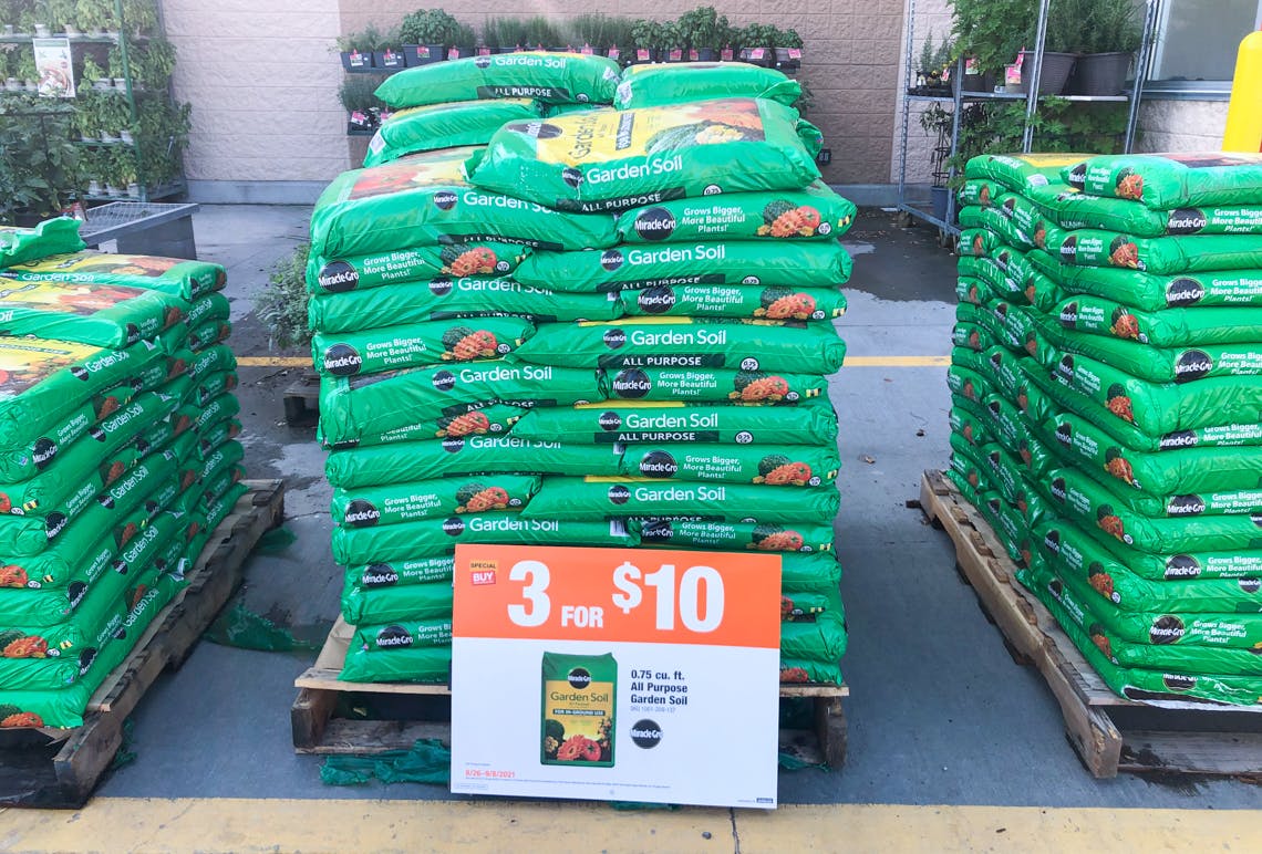 miracle gro garden soil stacked up on pallet with a sale sign in front of it.
