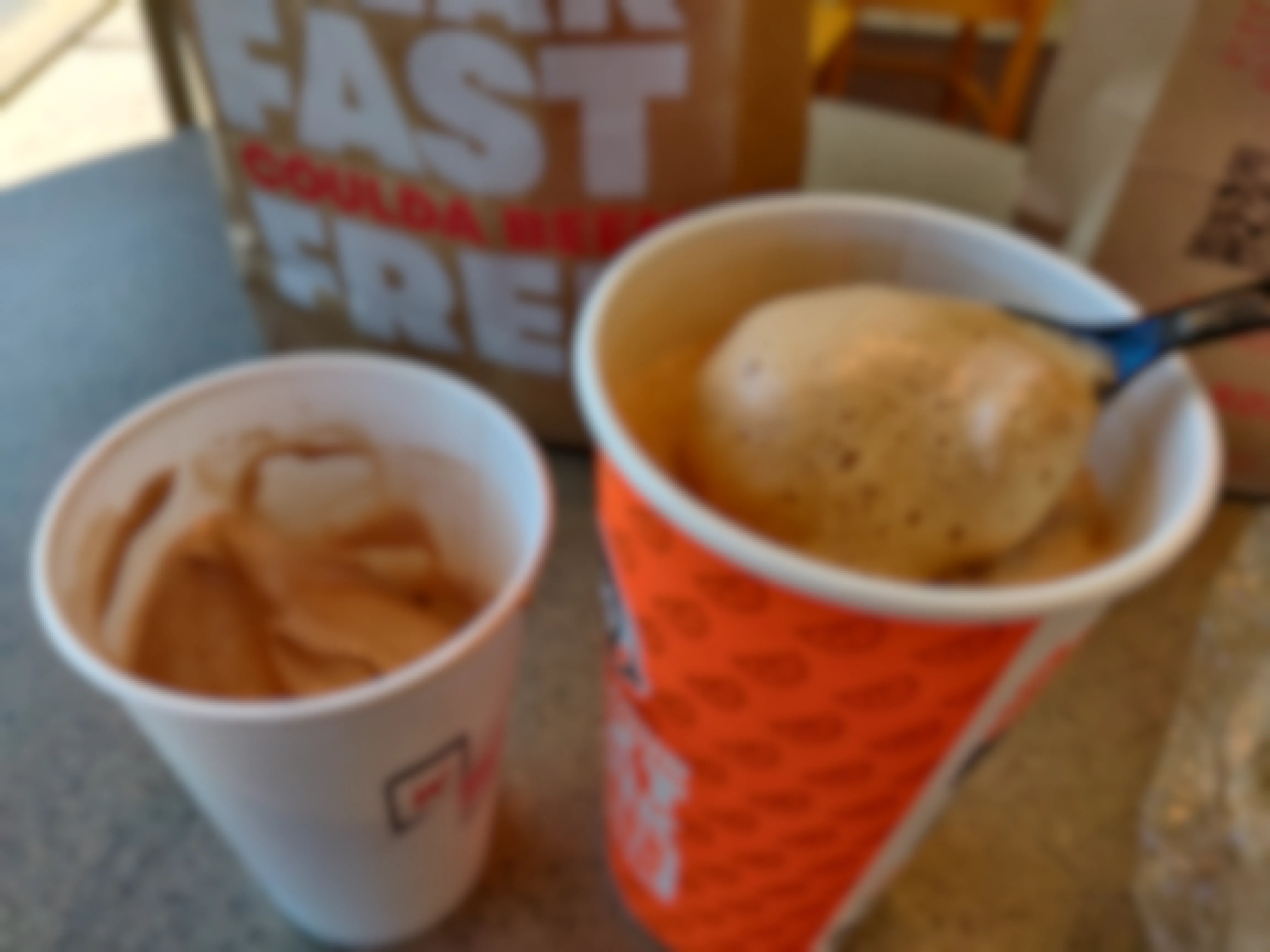 A Wendy's frosty and a Wendy's soda being mixed together with a spoon.