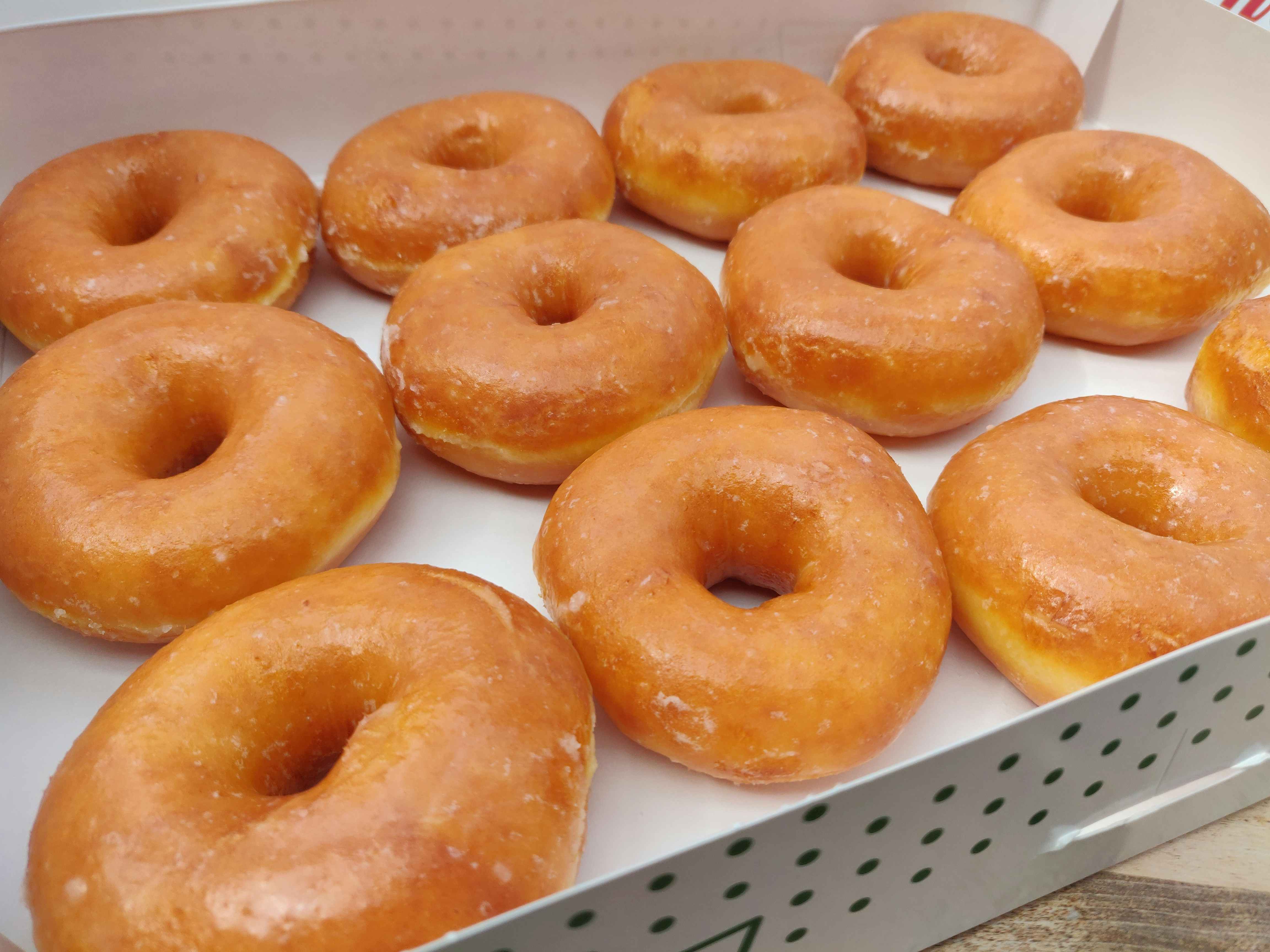 A dozen Krispy Kreme Original Glazed doughnuts in a box.