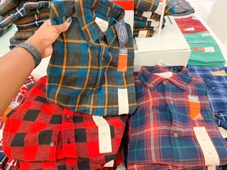 hand holding men's flannel shirt in front of display
