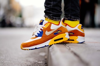 man wearing orange, yellow, and blue nike airmax sneakers