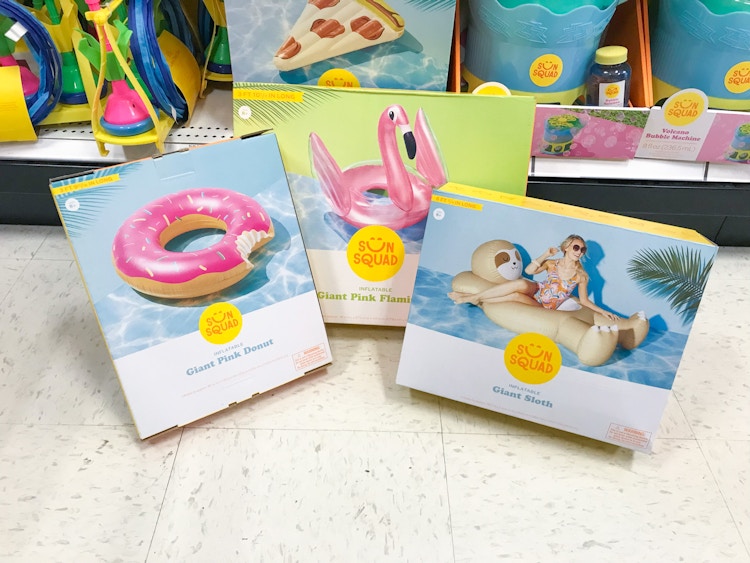 Three boxes for different Sun Squad inflatable pool floats sitting on the floor in an aisle in Target. 