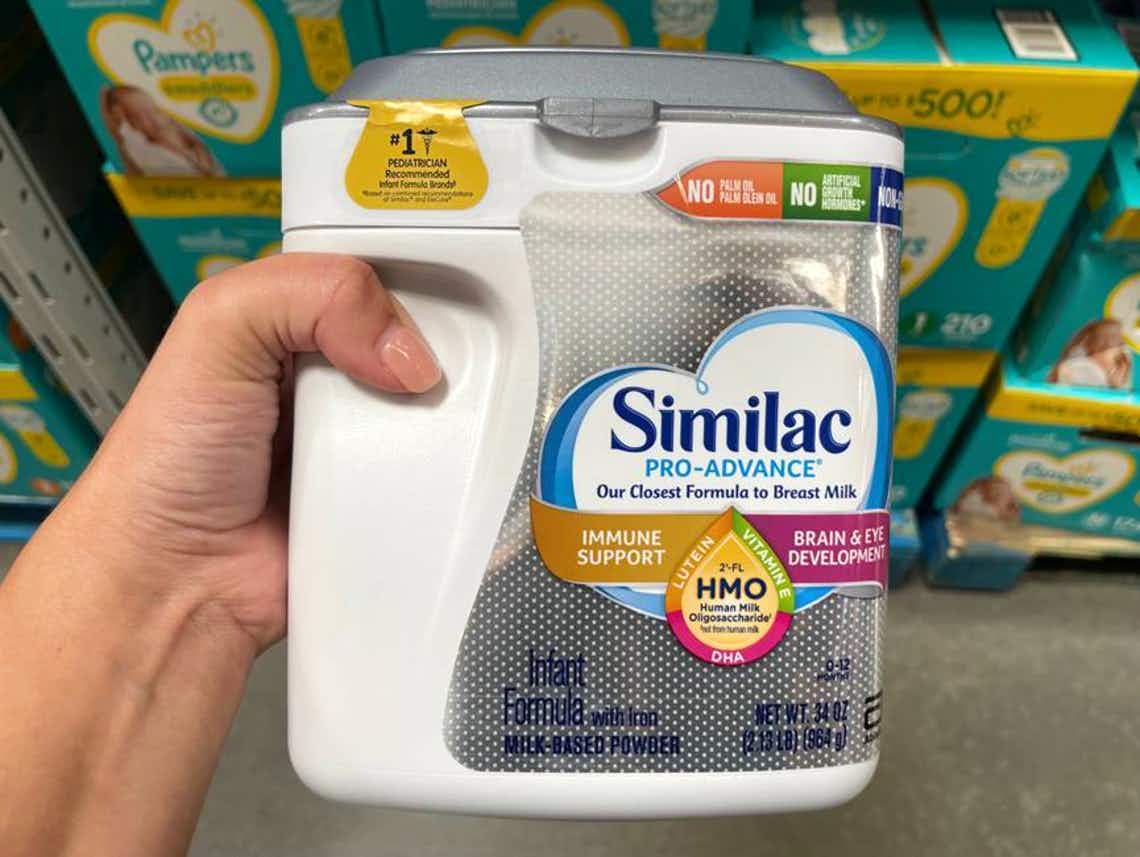 Someone holding a container of Similac baby formula in a store.