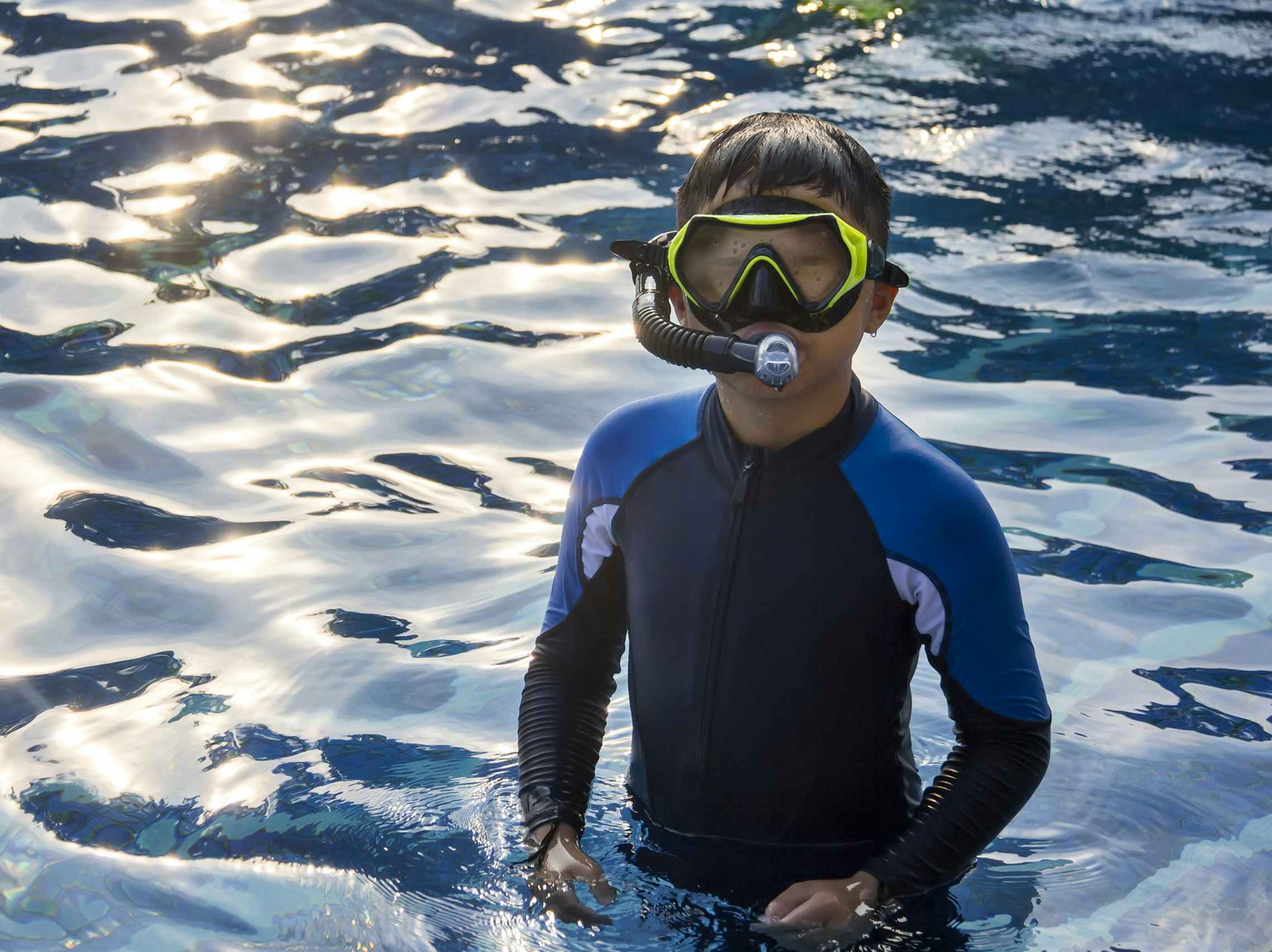 Kid standing in water with a snorkel on