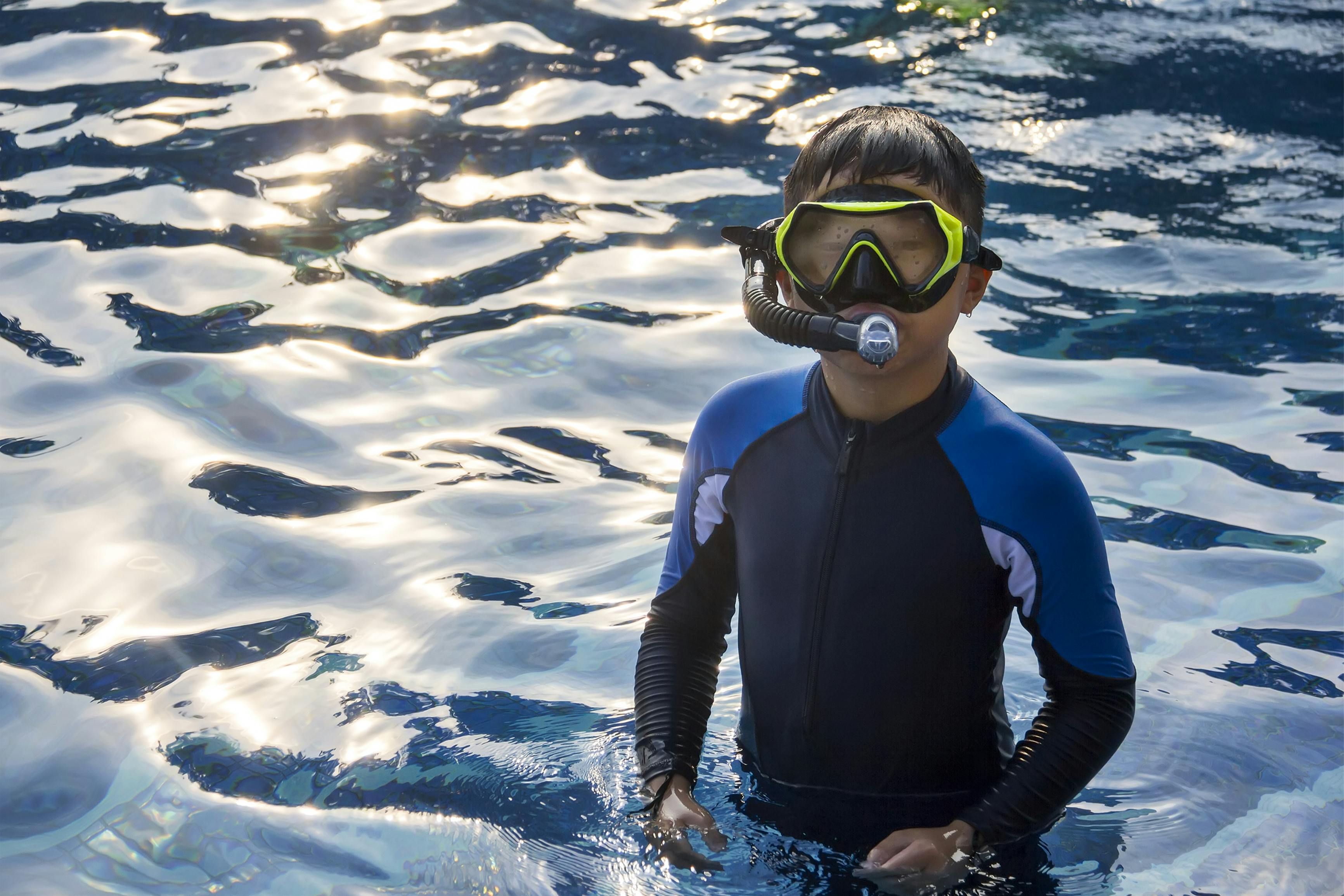 Kid standing in water with a snorkel on