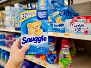hand holding out box of Snuggle dryer sheets in front of Walmart store shelf