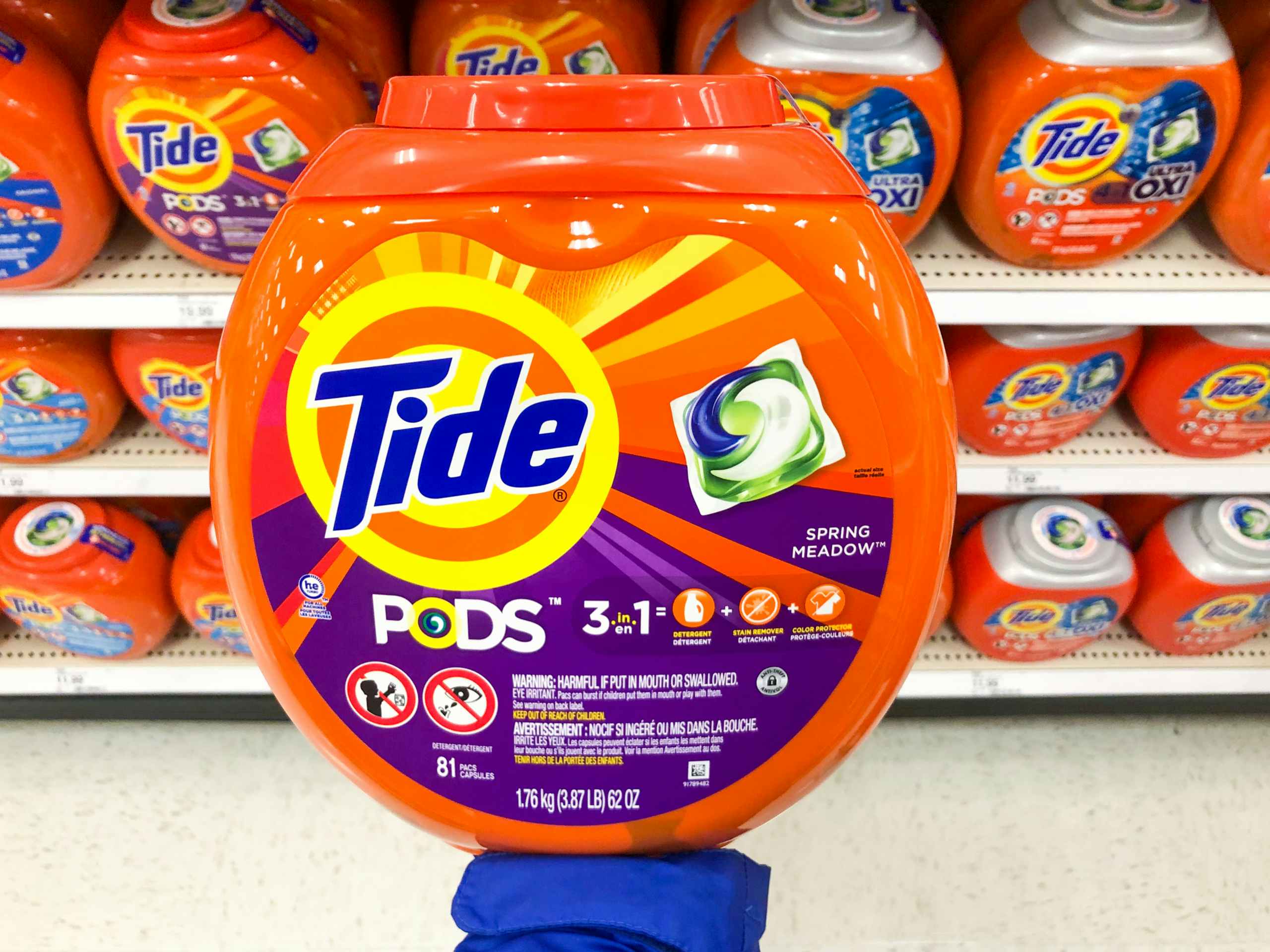 palm of hand holding up a large container of Tide pods in front of the Tide pods aisle at Target