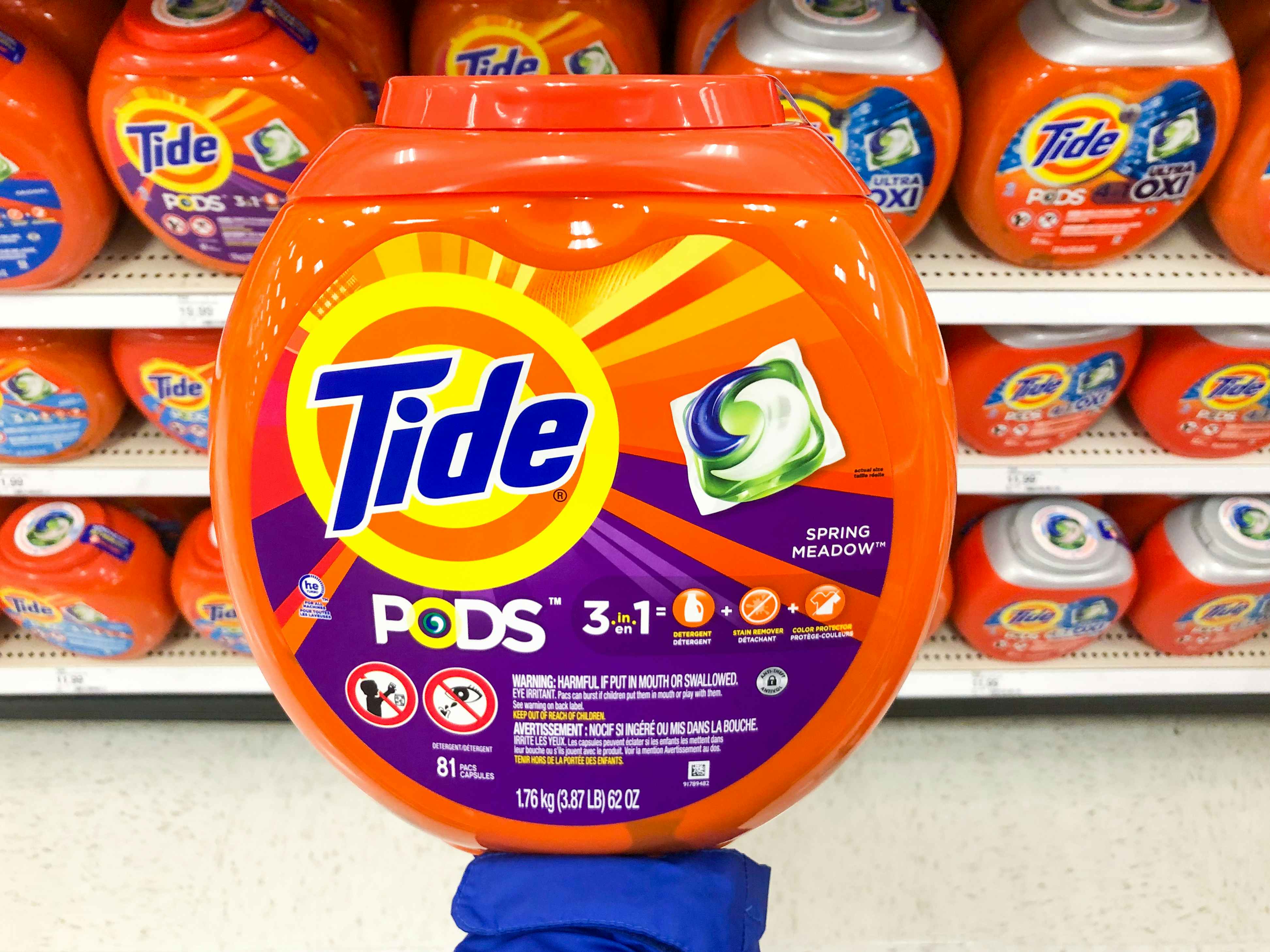 palm of hand holding up a large container of Tide pods in front of the Tide pods aisle at Target