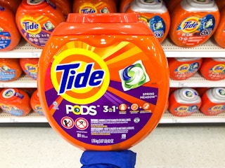palm of hand holding up a large container of Tide pods in front of the Tide pods aisle at Target