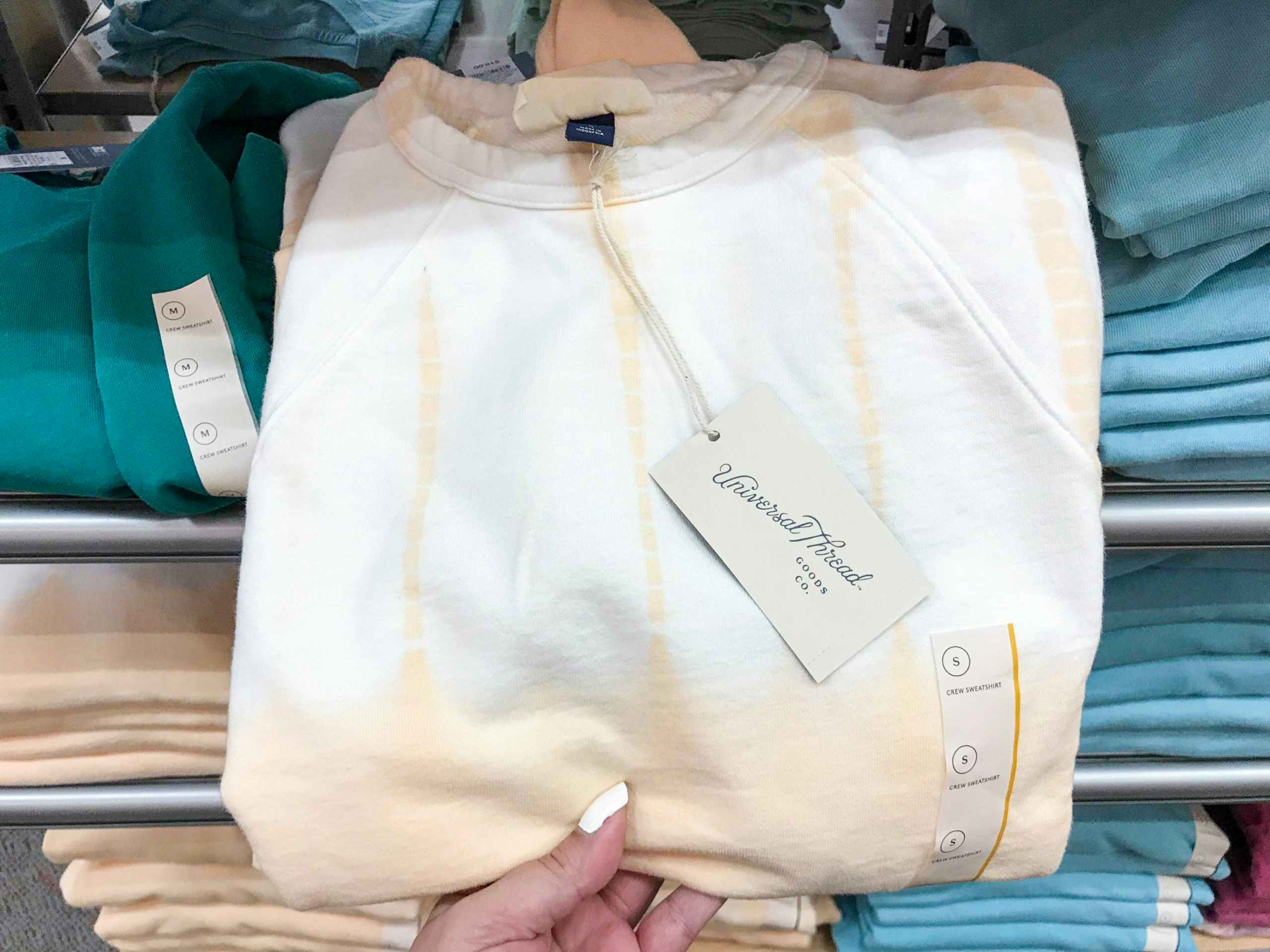hand holding sweatshirt from Target in front of sweatshirt display