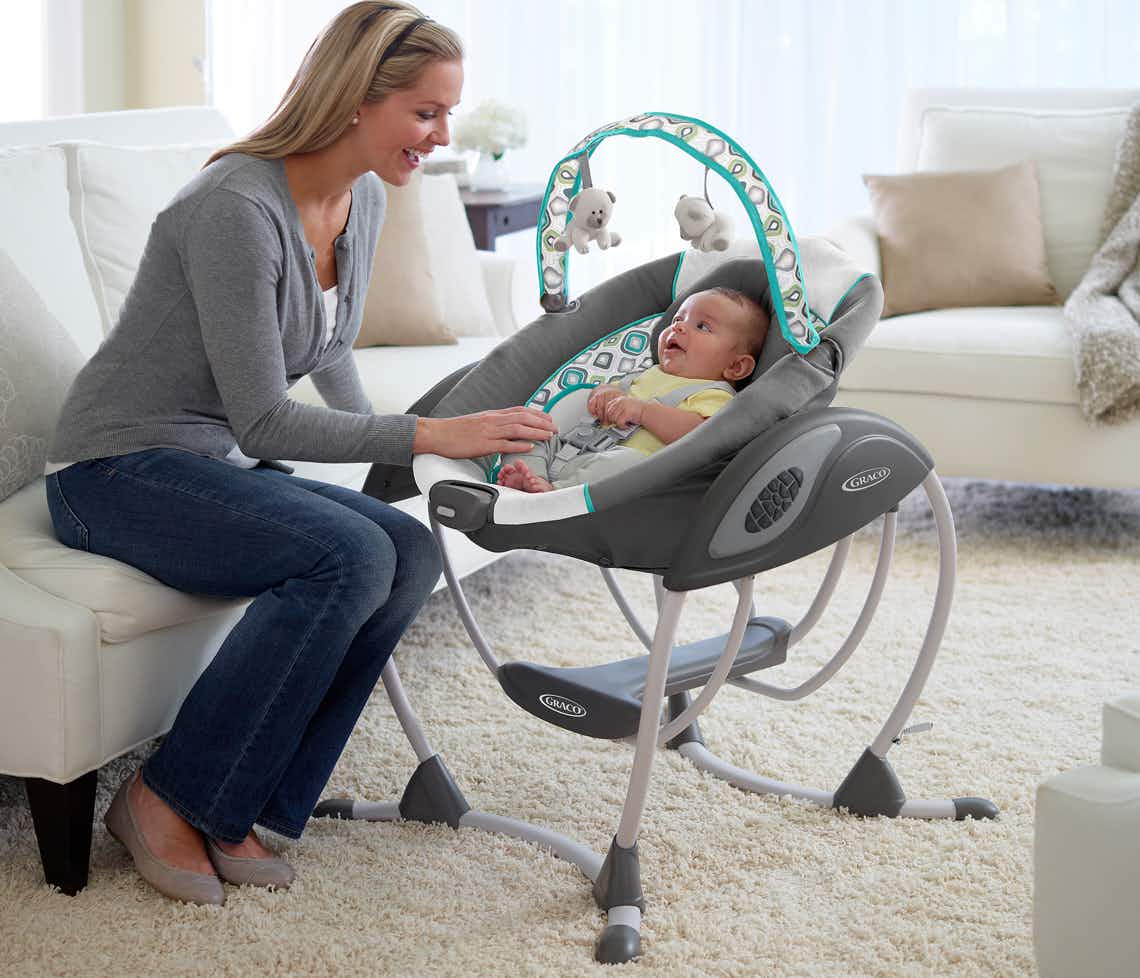 stock photo of woman playing with baby in graco baby swing