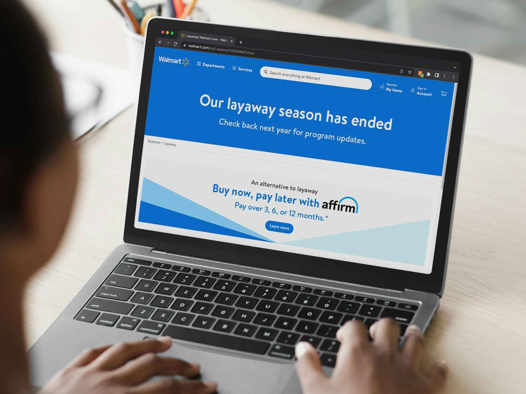 A person using a laptop displaying the Walmart Layaway page on their website which reads, "Our layaway program has ended. Check back next year for program updates" and an advertisement for Affirm below the message.