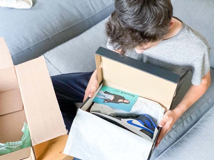 boy opening shoe box with stockx card in it