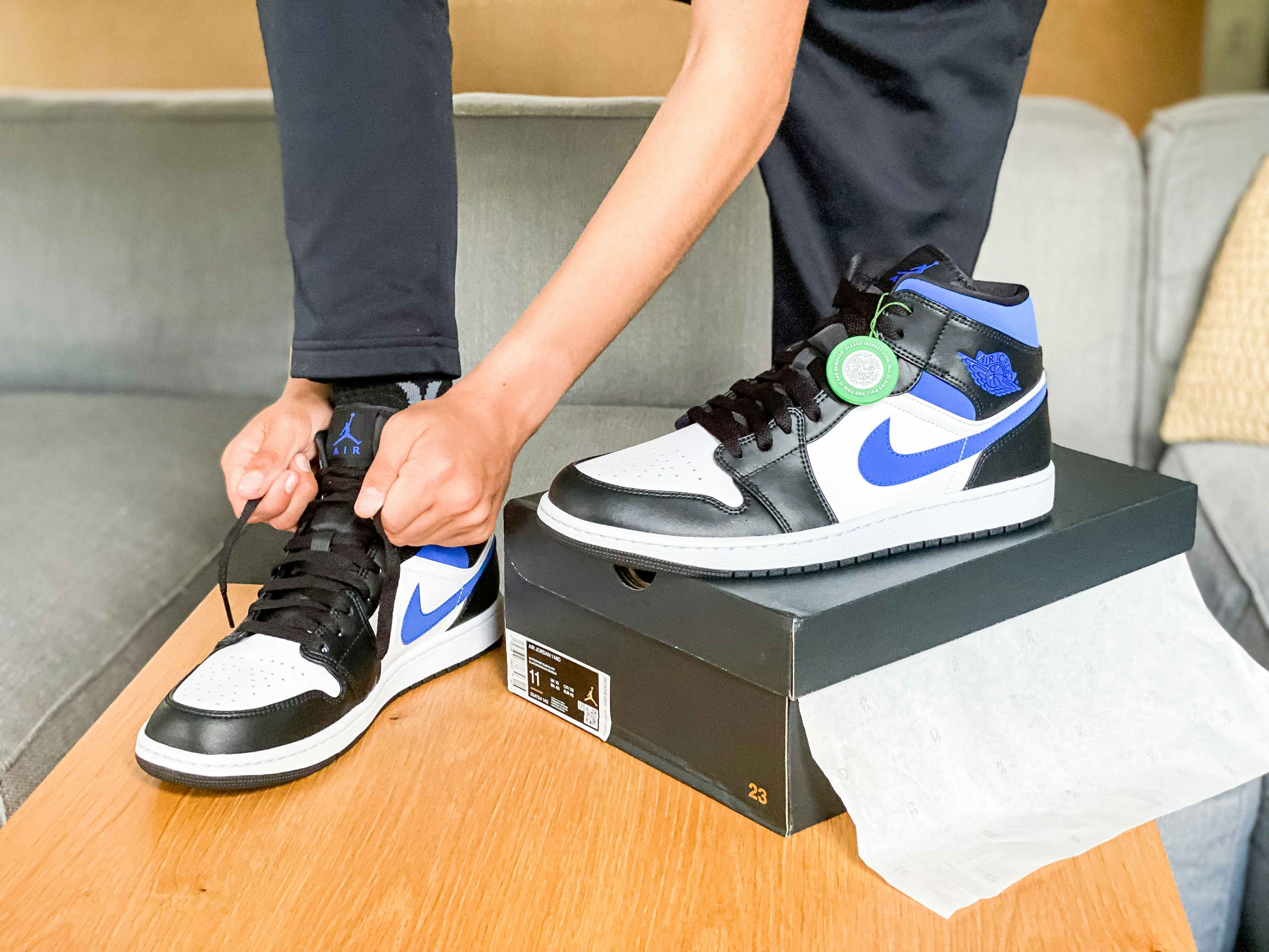 someone tying nike sneakers on a table