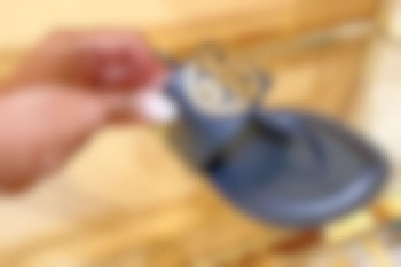A person touching the strap on a pair of Tory Burch sandals.