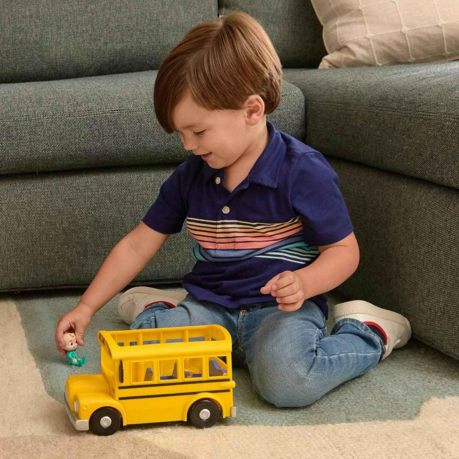 A boy playing with a CoComelon yellow school bus.