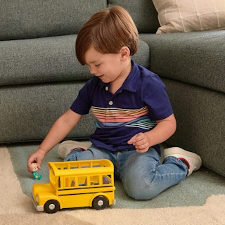 A boy playing with a CoComelon yellow school bus.
