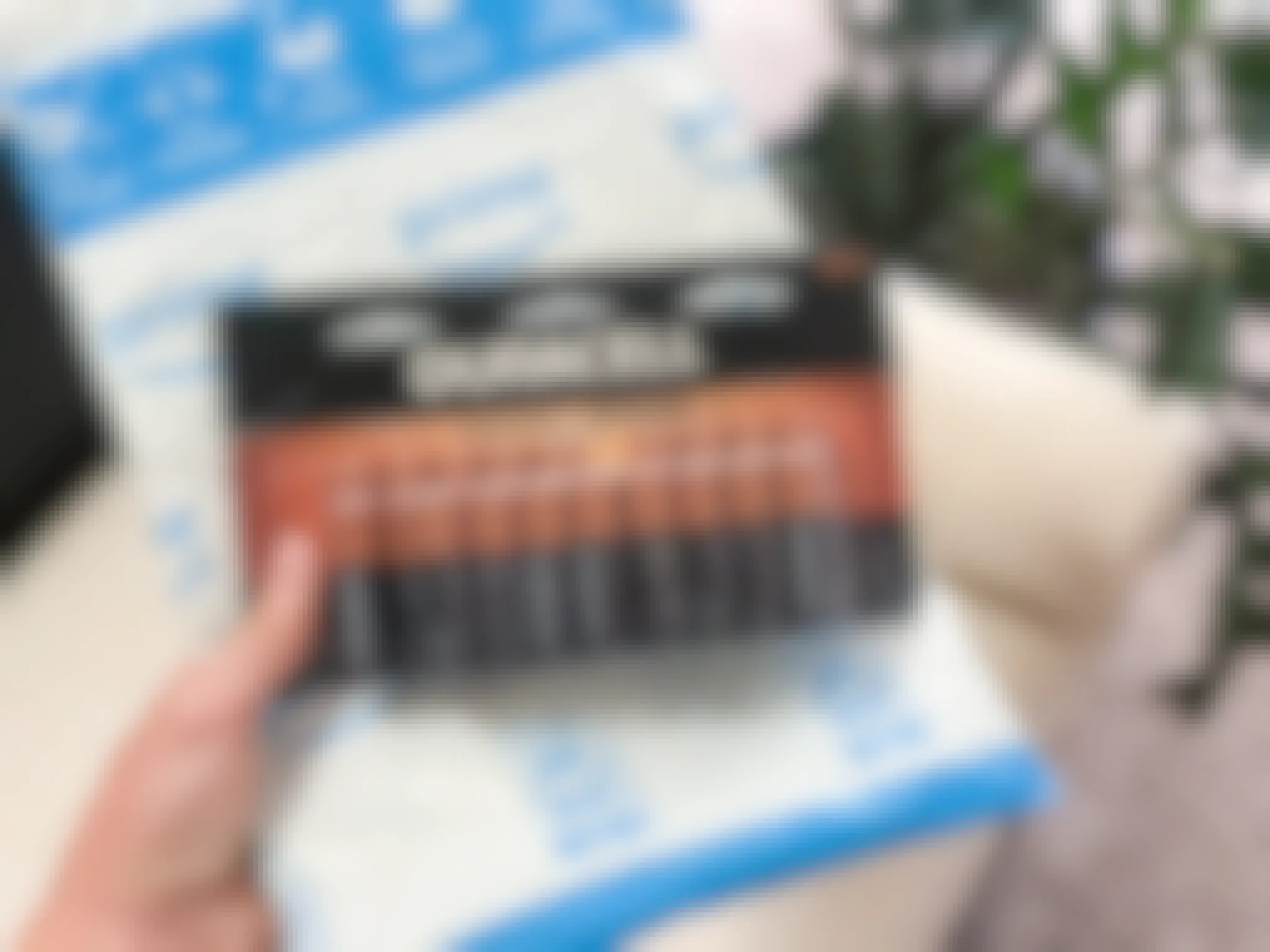 A person holding a pack of Duracell batteries.