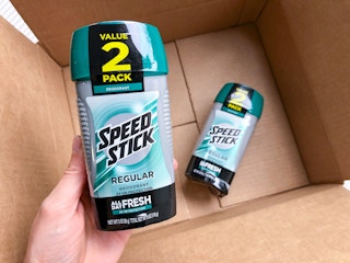 A hand holding Speed Stick deodrant over a delivery box.