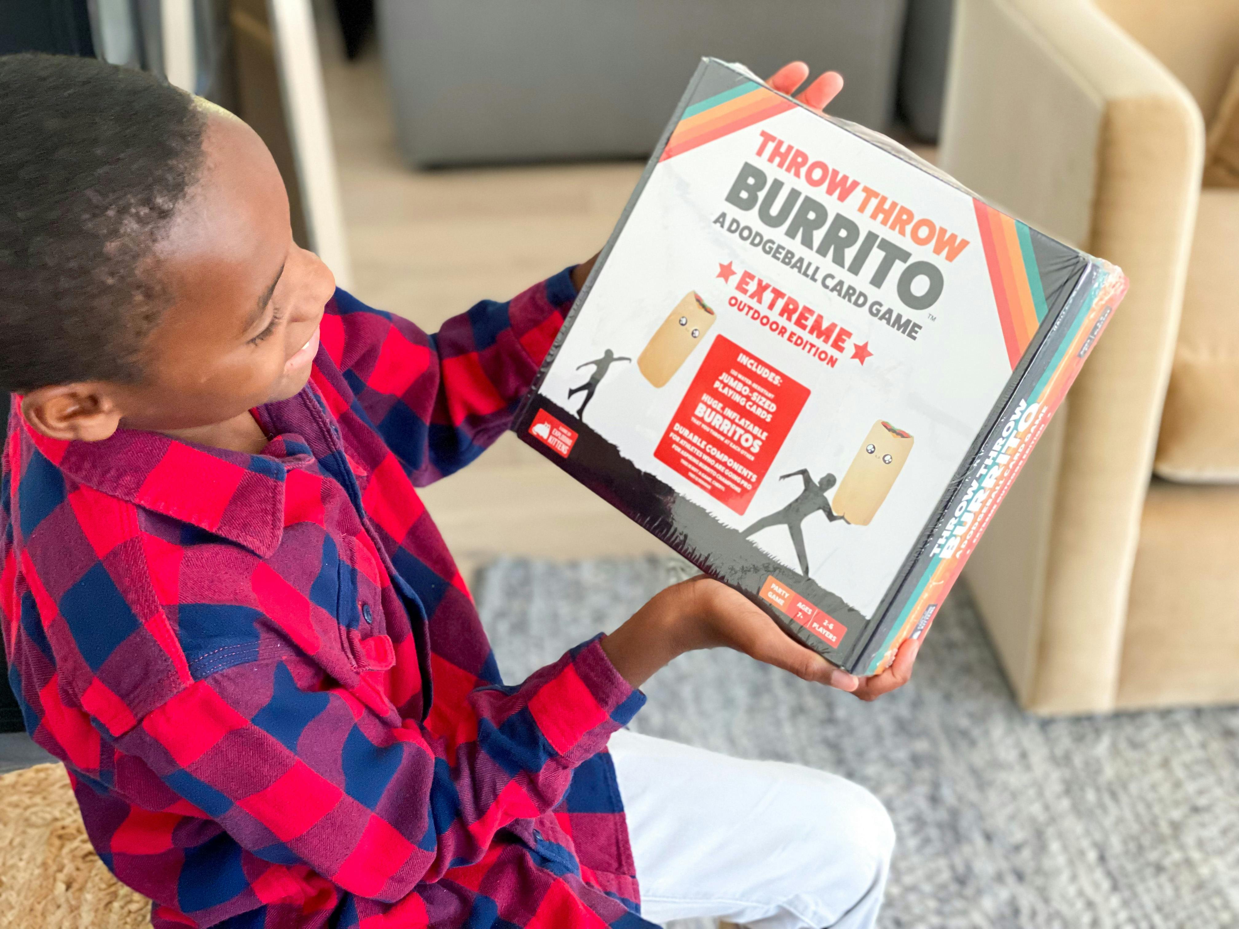 A young boy looking at the box of a Throw Throw Burrito game.