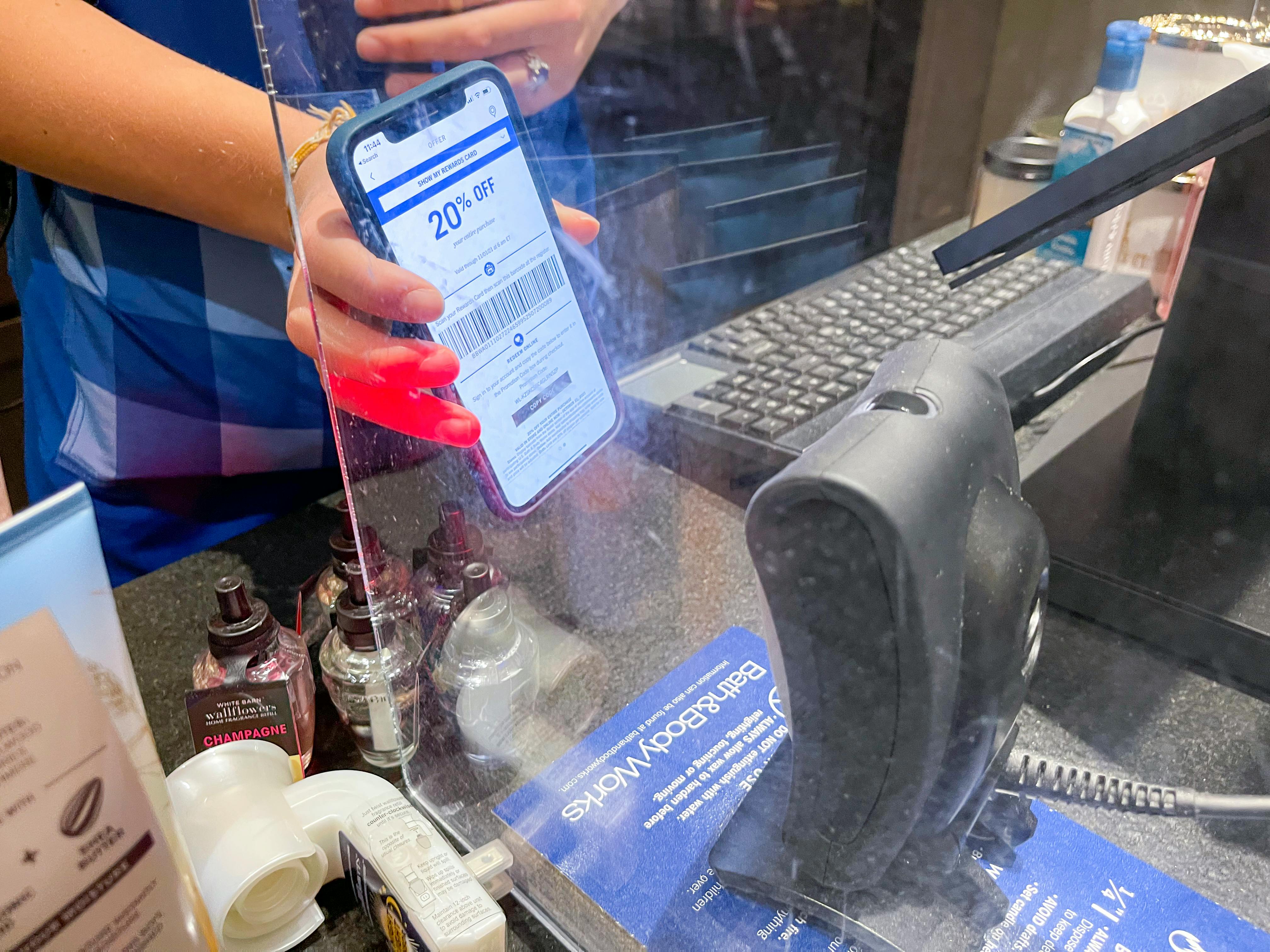 a cashier at Bath and body Works scanning a coupon on the app.