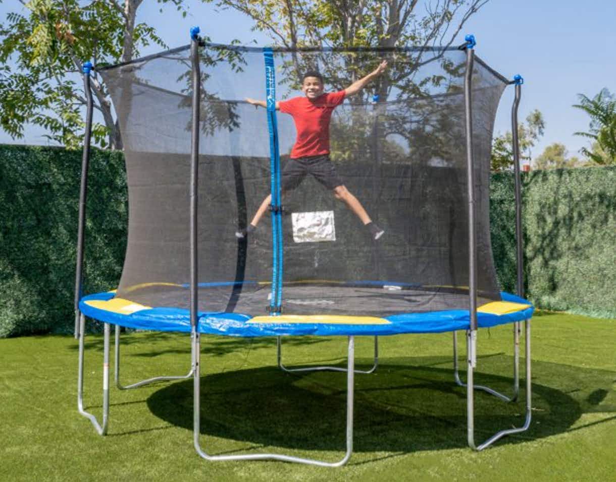 A child jumping on a Bounce Pro 12 foot trampoline in a backyard.