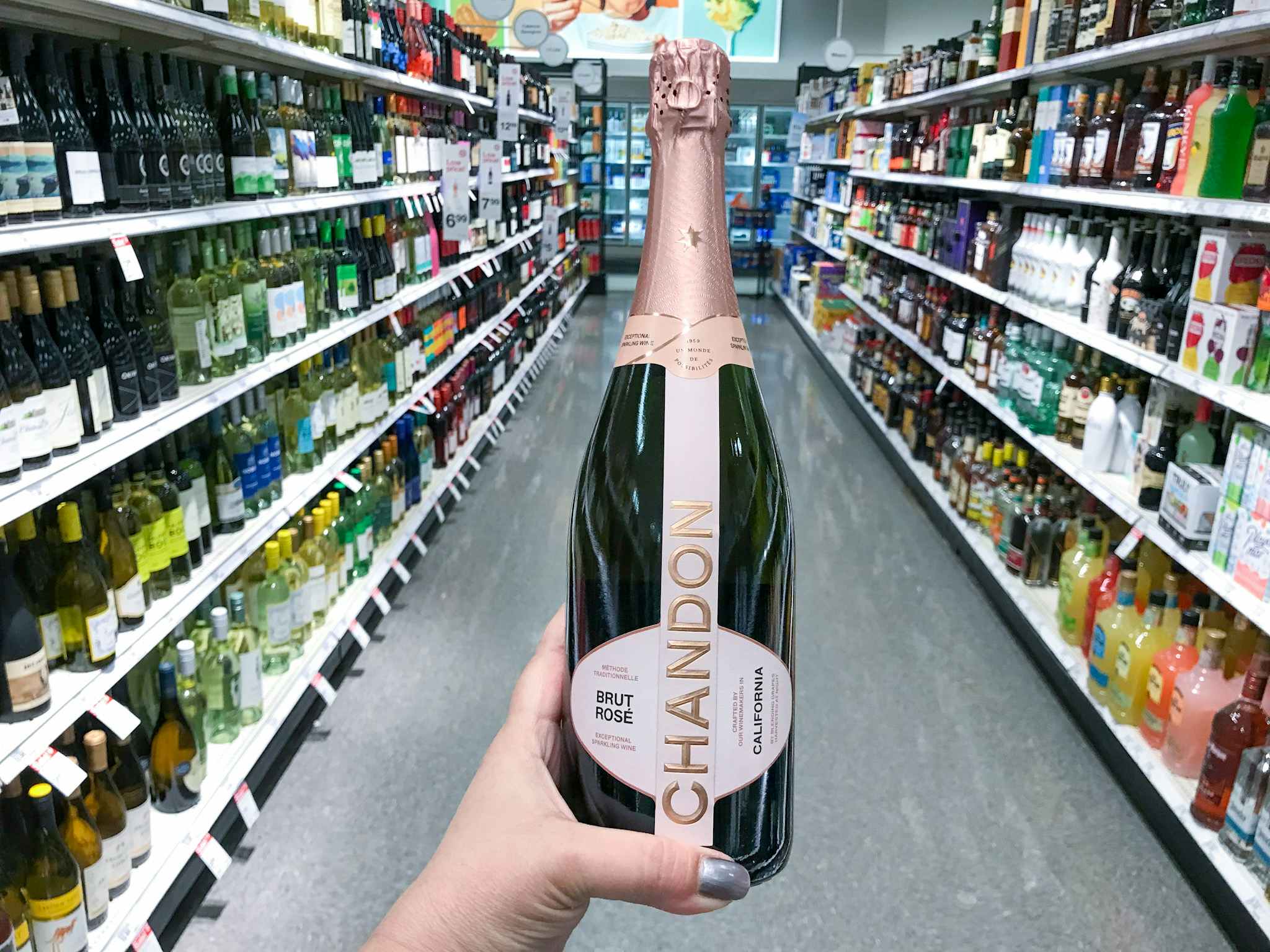 hand holding a bottle of chandon sparkling rose wine in a target aisle