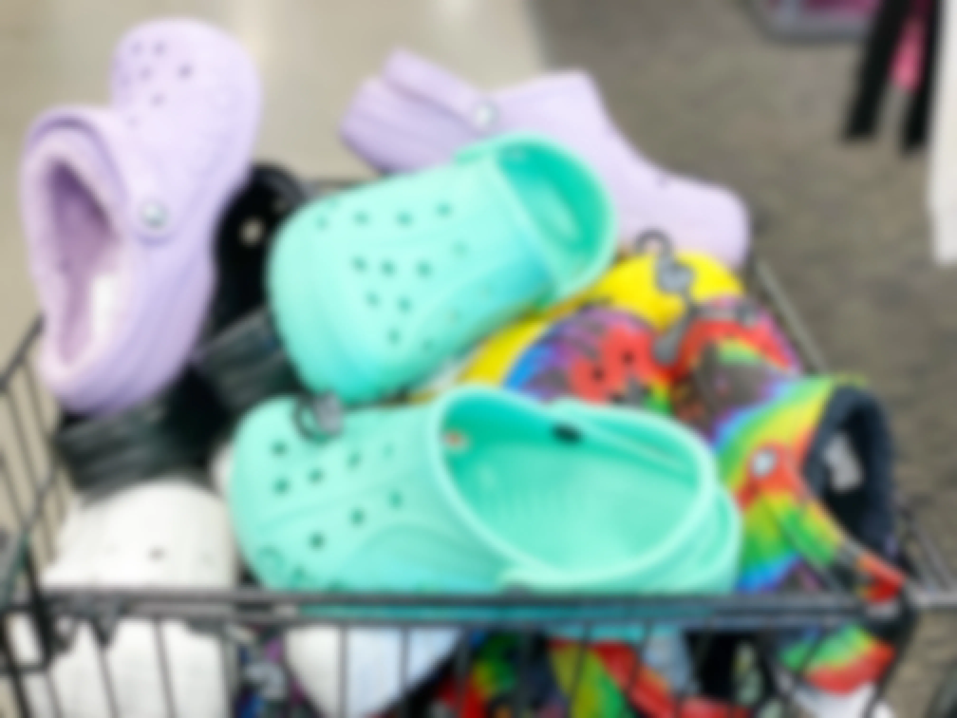 A shopping cart filled with pairs of Crocs inside a store.