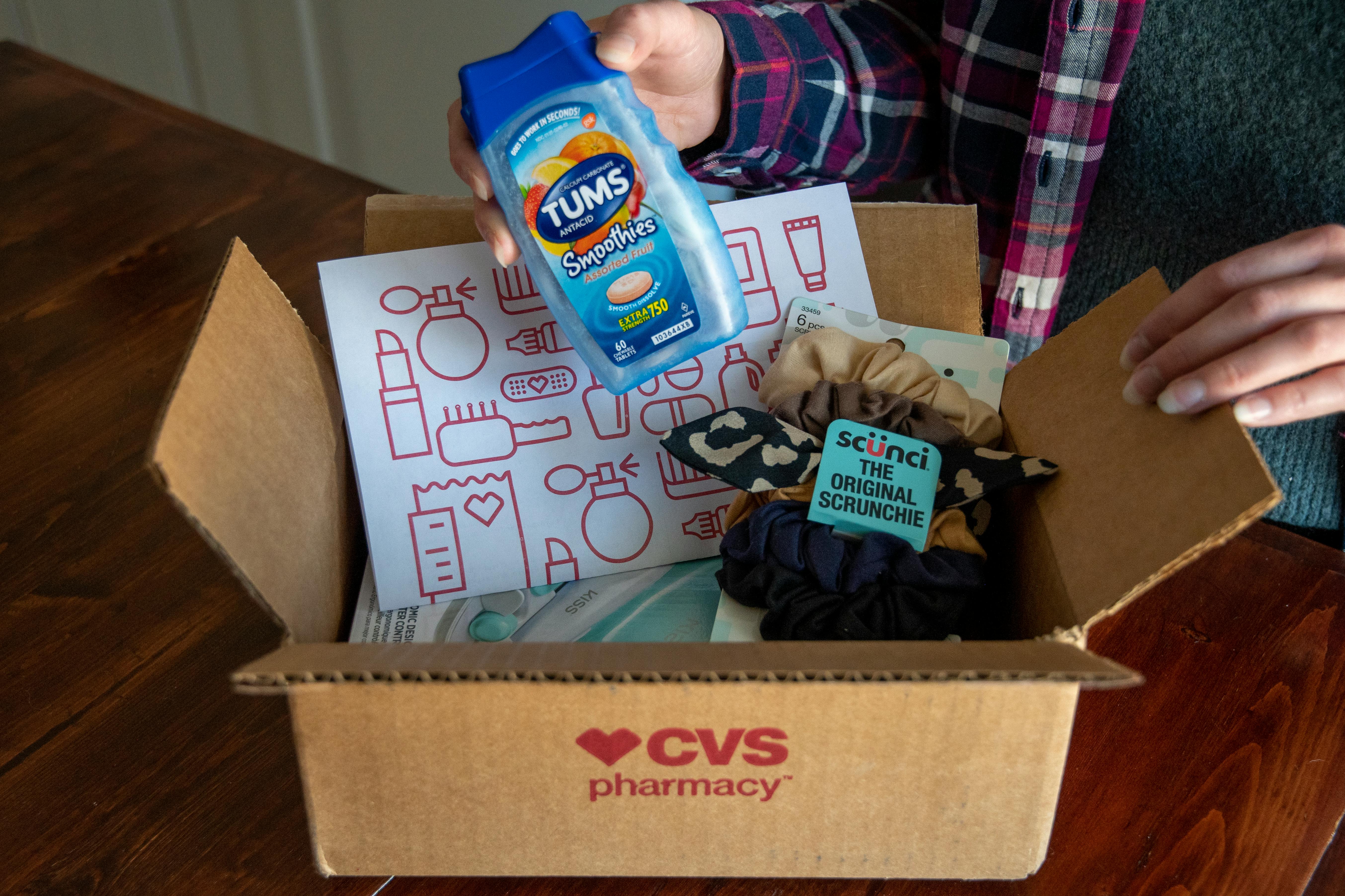 A person taking some Tums out of a CVS box filled with other products.