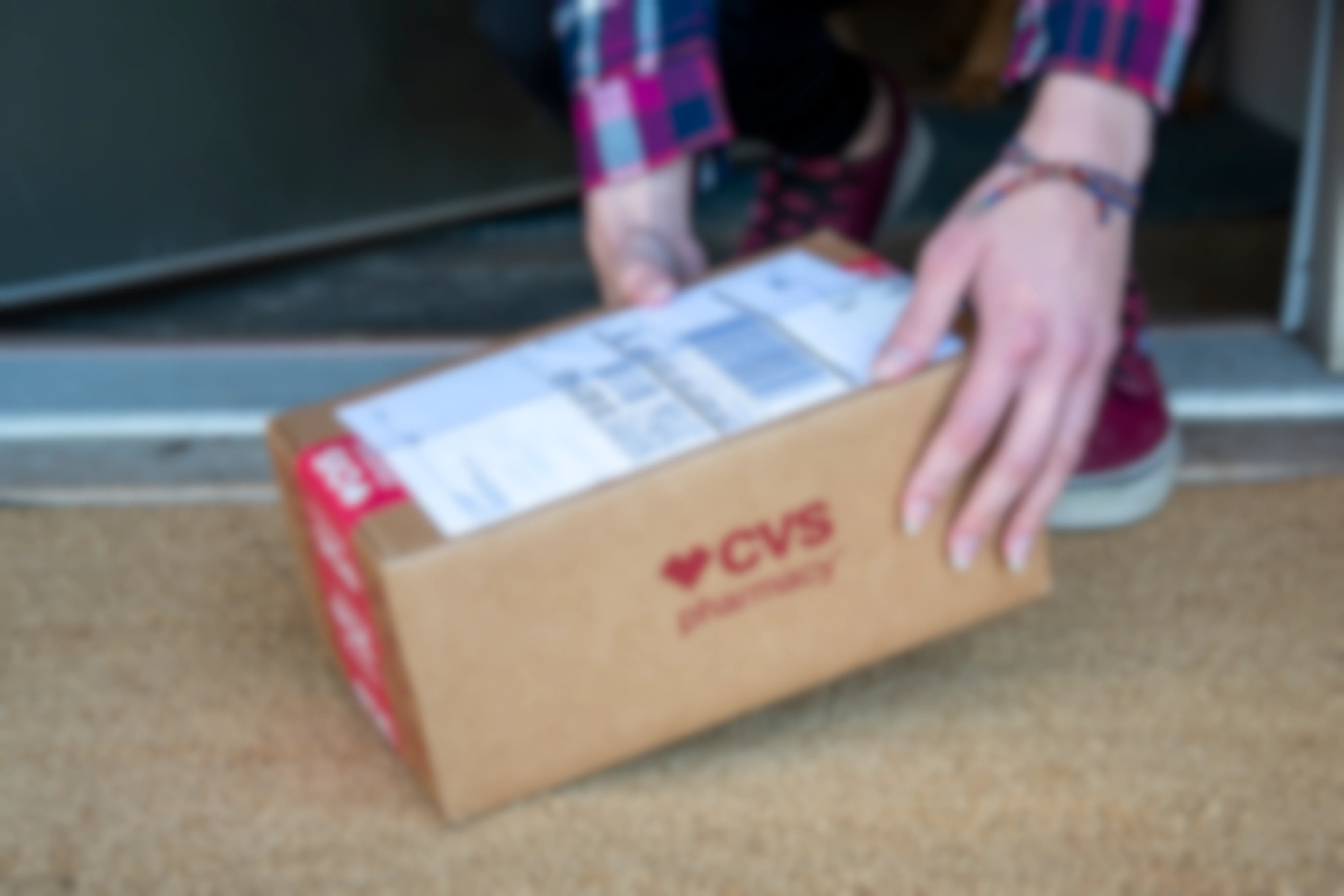 A person picking up a CVS deliver box from a doorstep