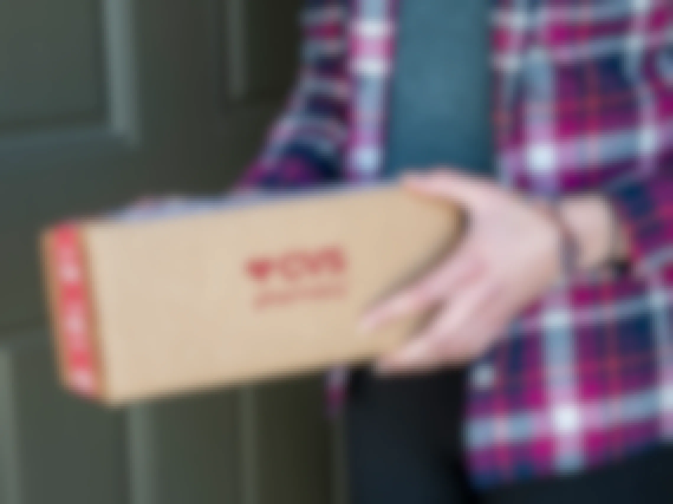 A person holding a CVS delivery box at a front door
