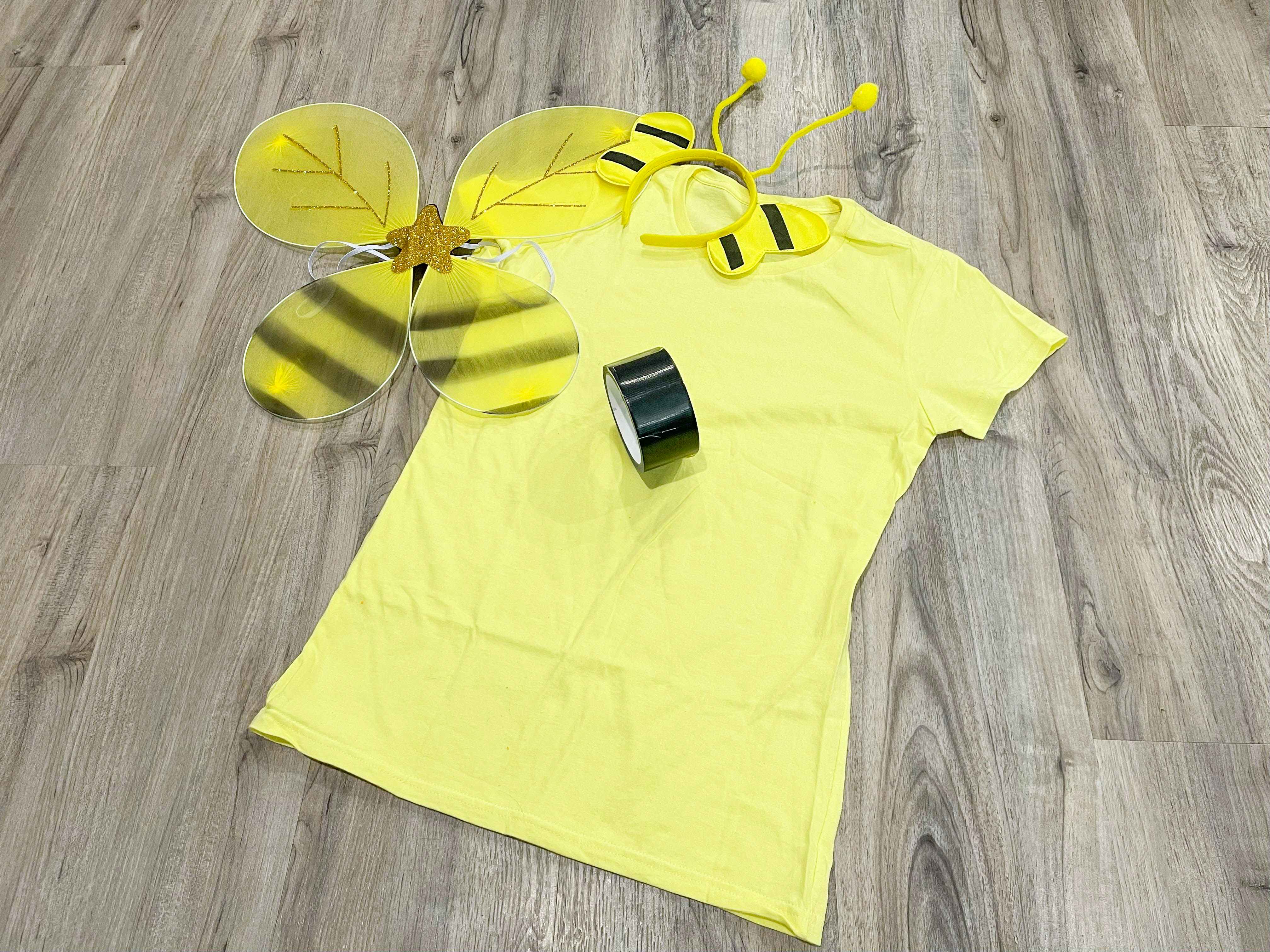 A yellow shirt and bee costume items lying on the floor together.