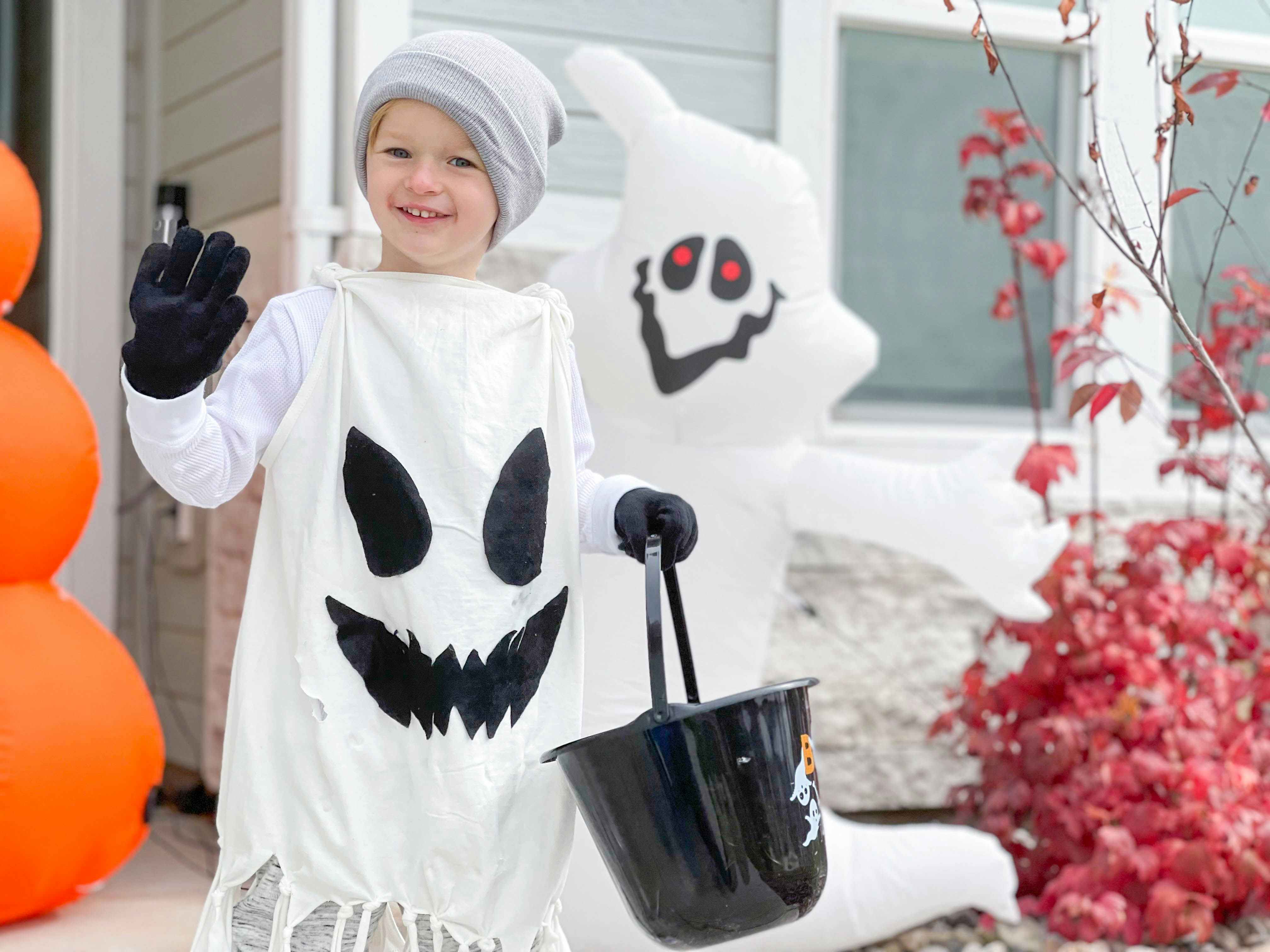 kid in ghost costume in front of door