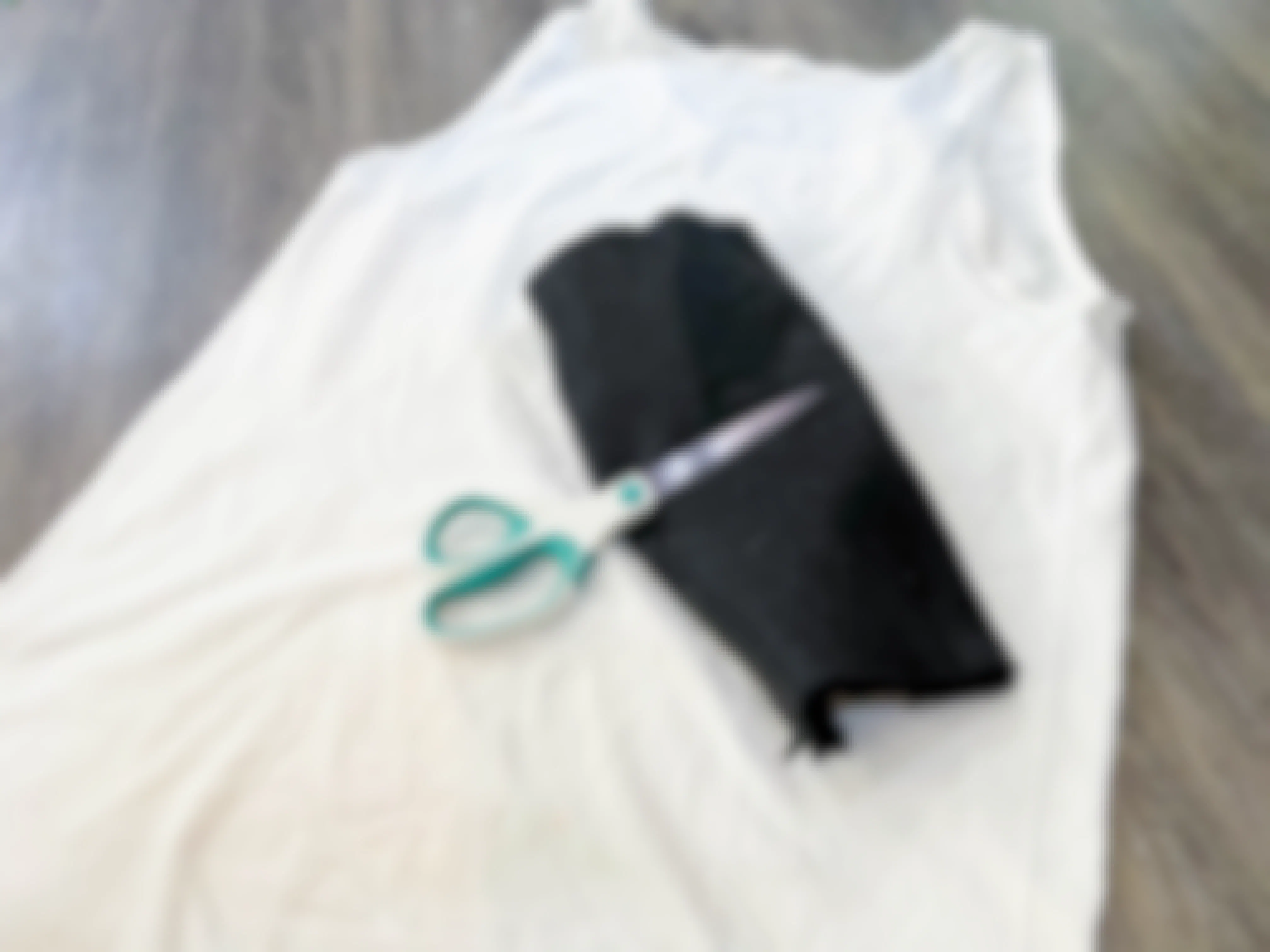 White shirt with black felt and scissors laid out on a floor