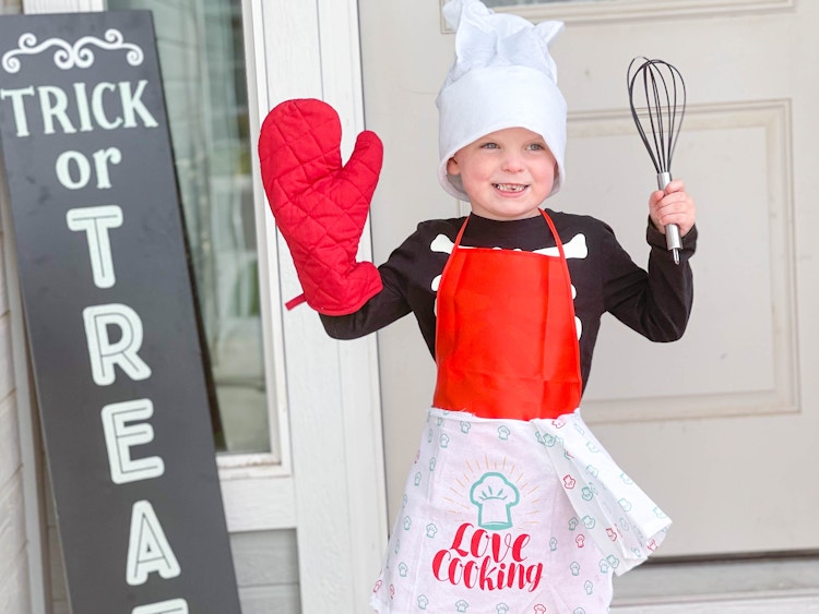 kid in chef costume in front of door