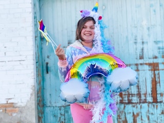A child wearing rainbow accessories and a unicorn headband