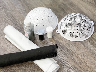 black and white felt, paint and painted colanders set up on the floor