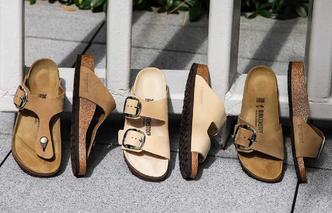 Three pairs of Birkenstock sandals displayed leaning up against a fence.
