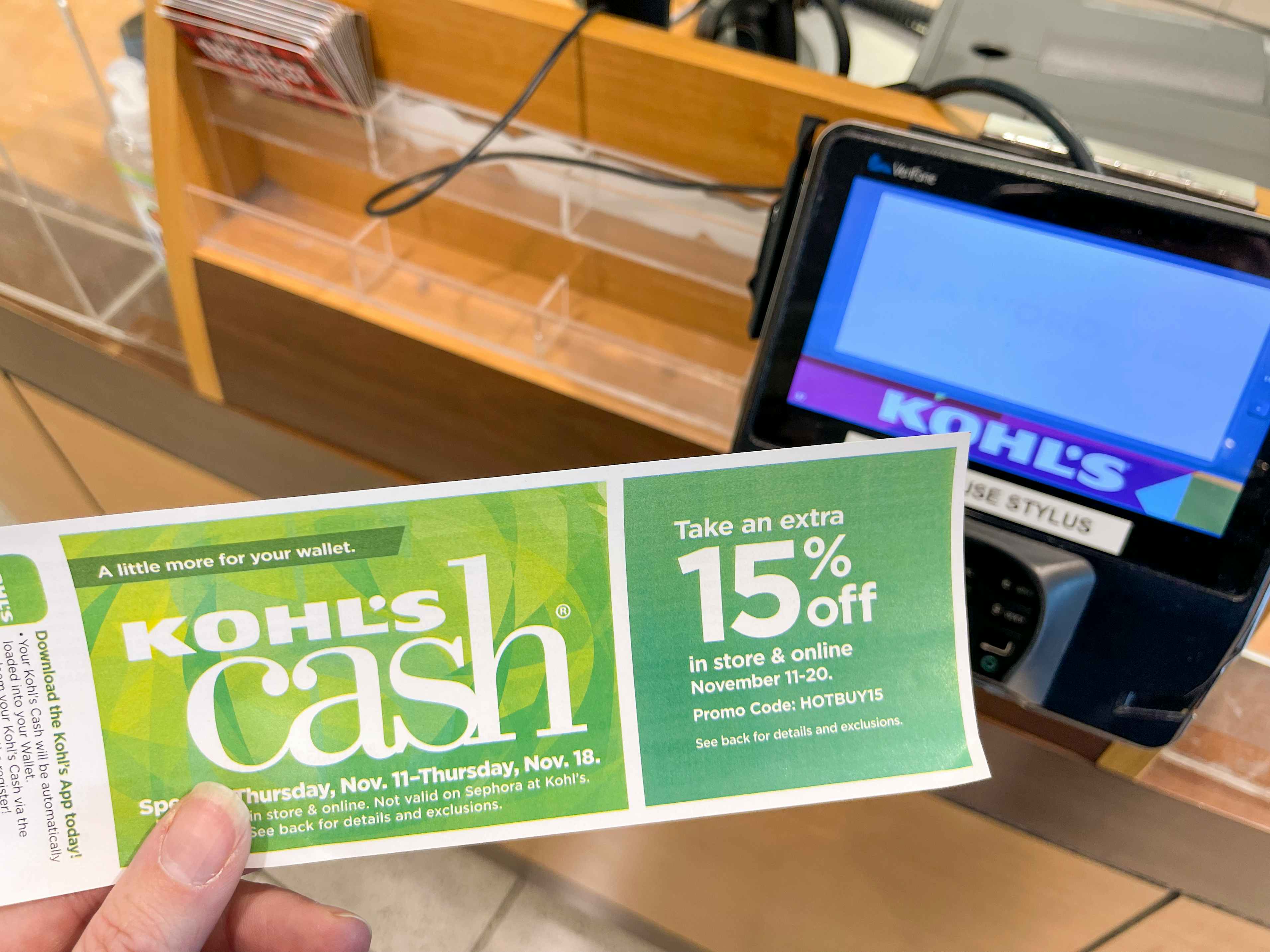 A person holding Kohl's cash at checkout
