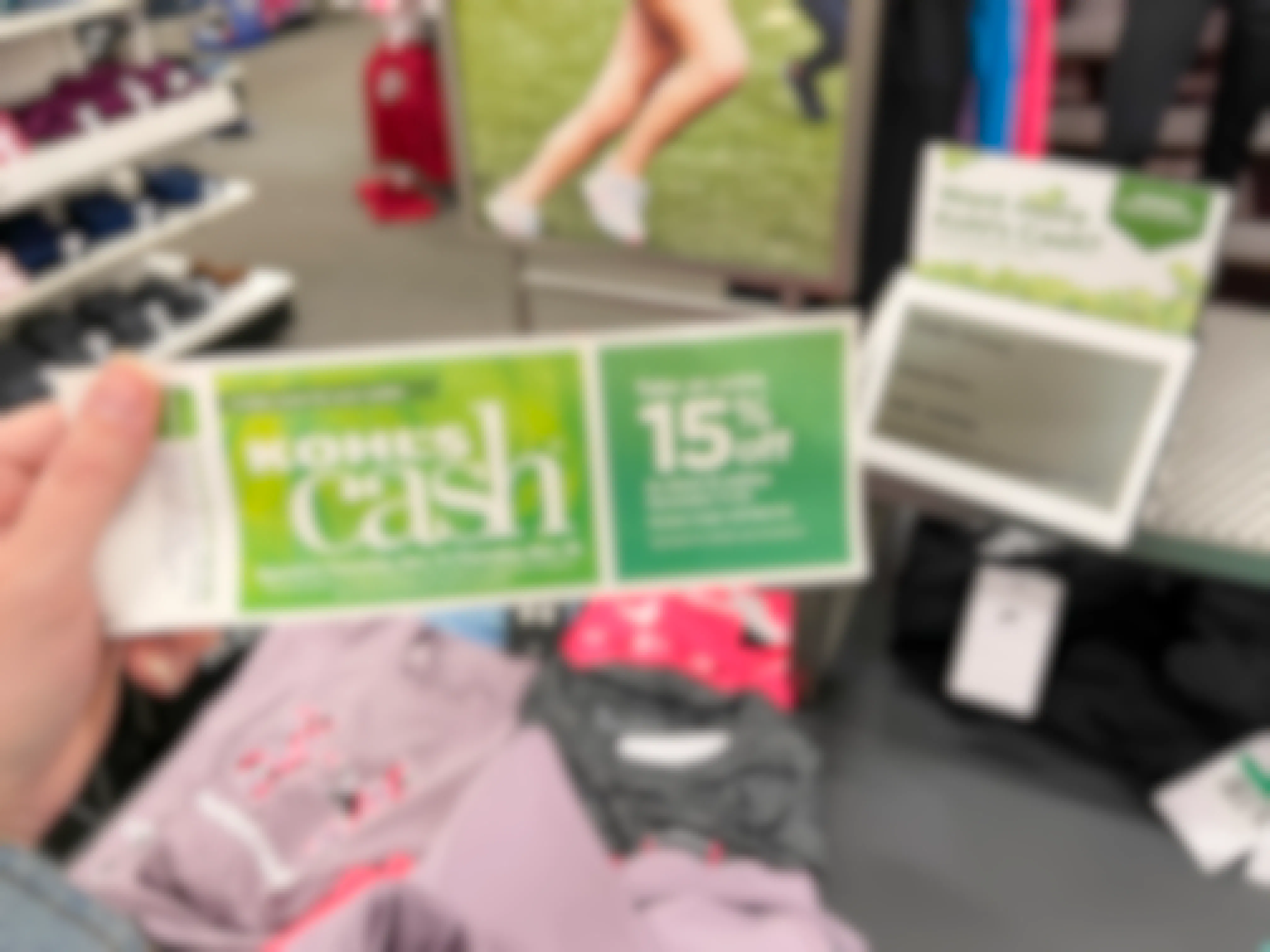 A person holding Kohl's cash near a sales sign
