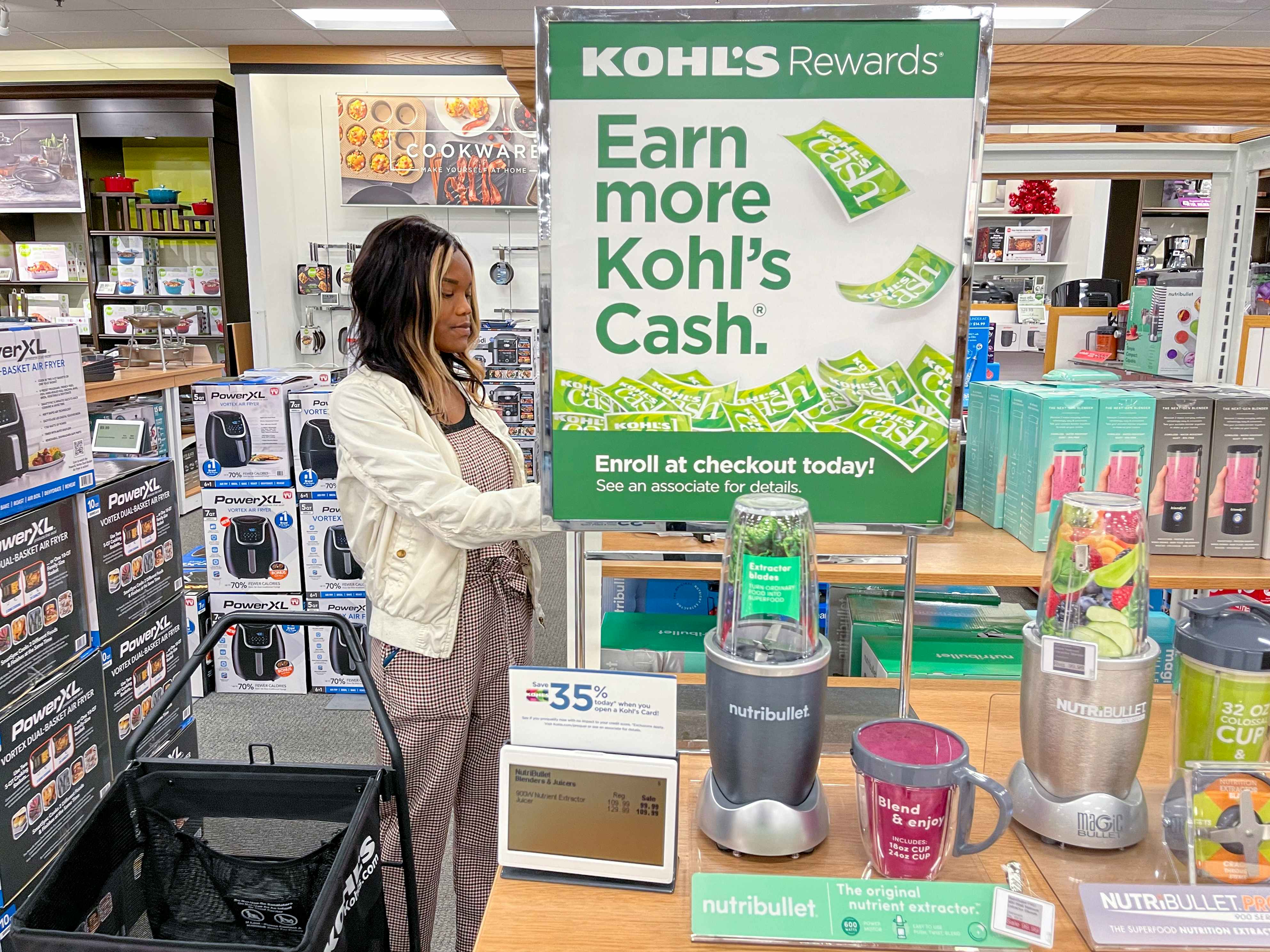 A woman shopping next to a Kohl's cash sign on a display of Nutribullet kitchen appliances at Kohl's.