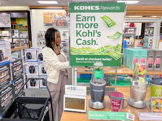 A woman shopping next to a Kohl's cash sign on a display of Nutribullet kitchen appliances at Kohl's.